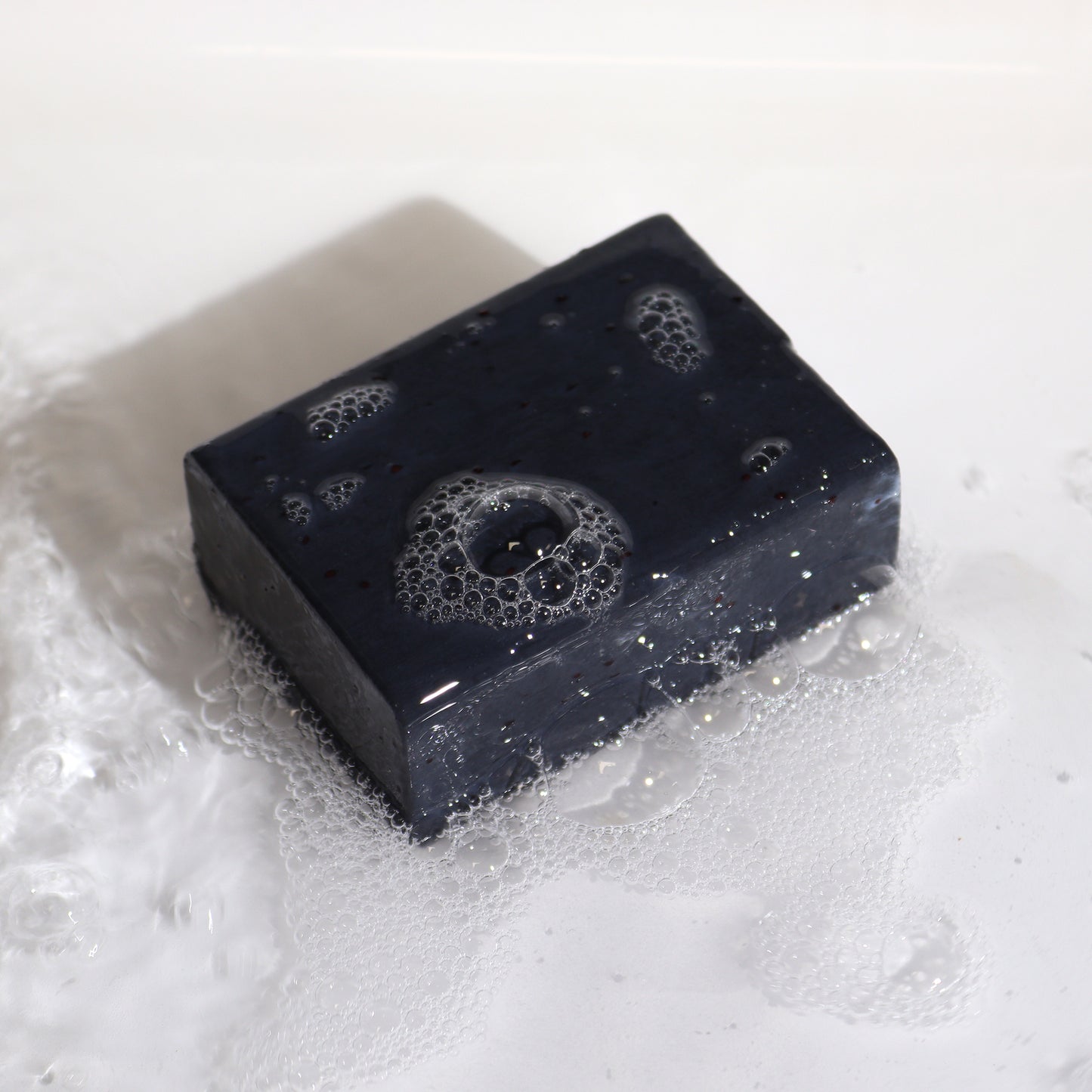 Black Klay soap with bubbles on a white background