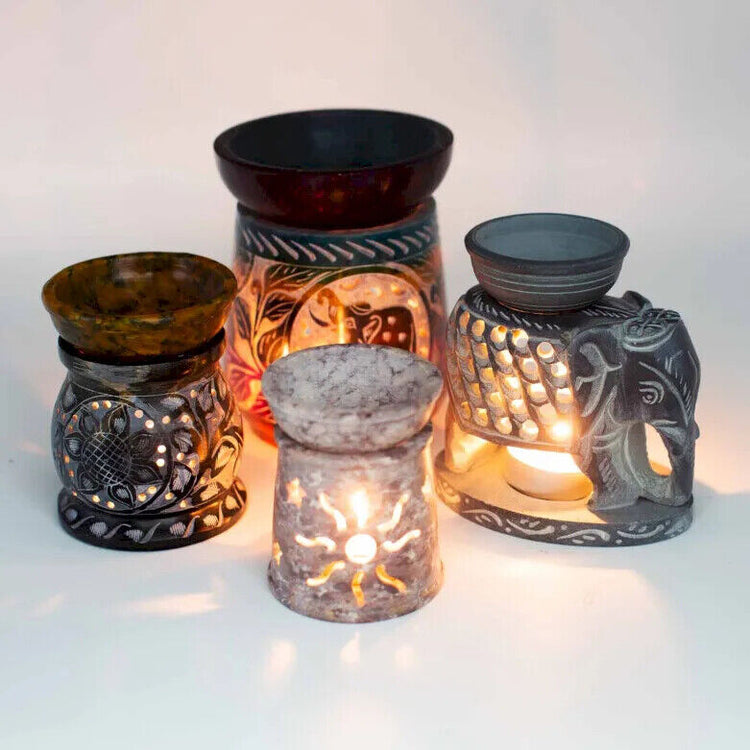 A collection of sandstone oil burners in various designs, with one piece being carved with an Elephant design, and others with abstract patterns.