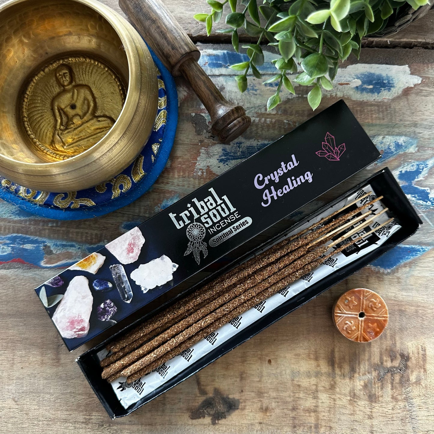 Box of Tribal Soul Crystal Healing incense sticks on a wooden surface with a singing bowl and crystals.