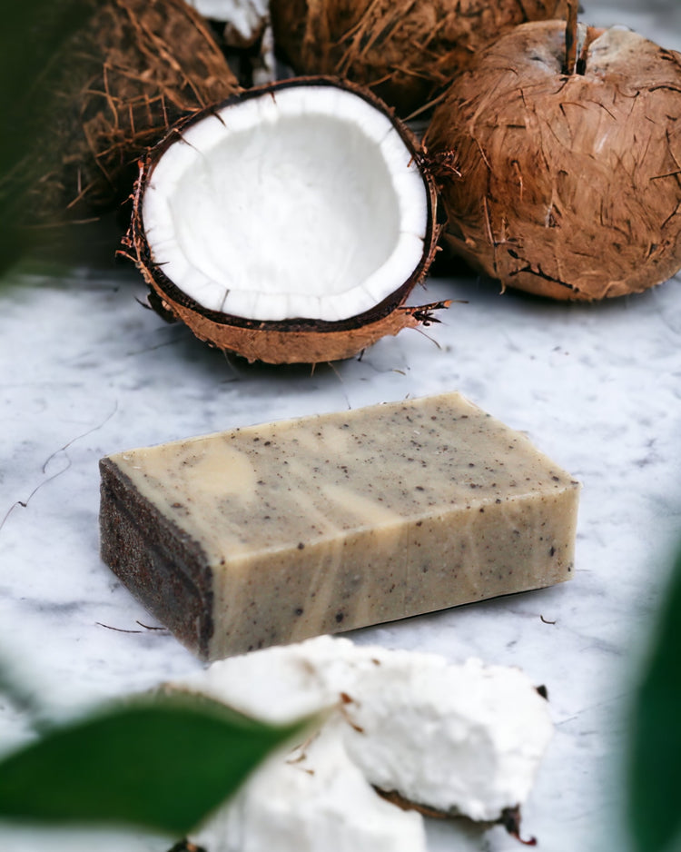 A Slice of coconut-infused soap with olive oil, presented on a white surface, surrounded by natural elements including coconuts and leaves.
