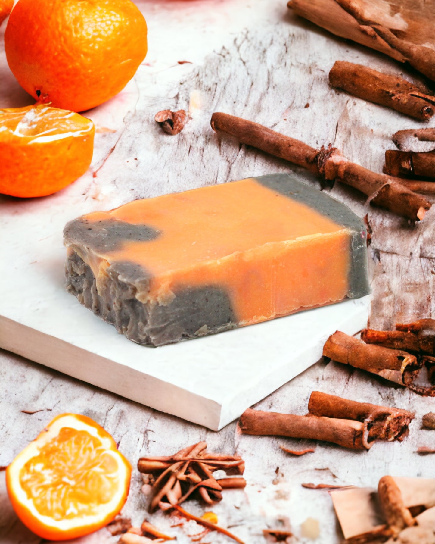 A bar of olive oil soap with cinnamon and orange, displayed with spices and citrus fruit slices around it.