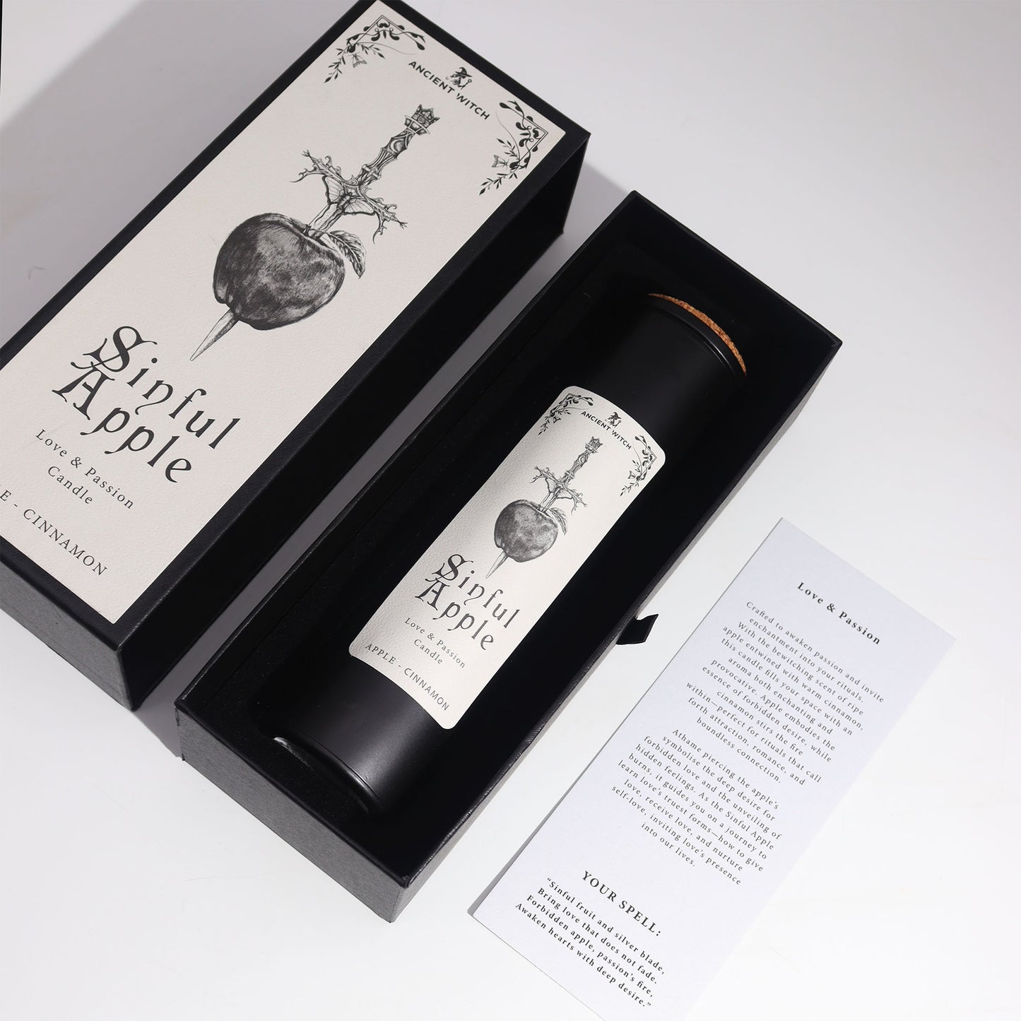 Overhead view Candle labeled 'Sinful Apple' in a black box with decorative design on a white background