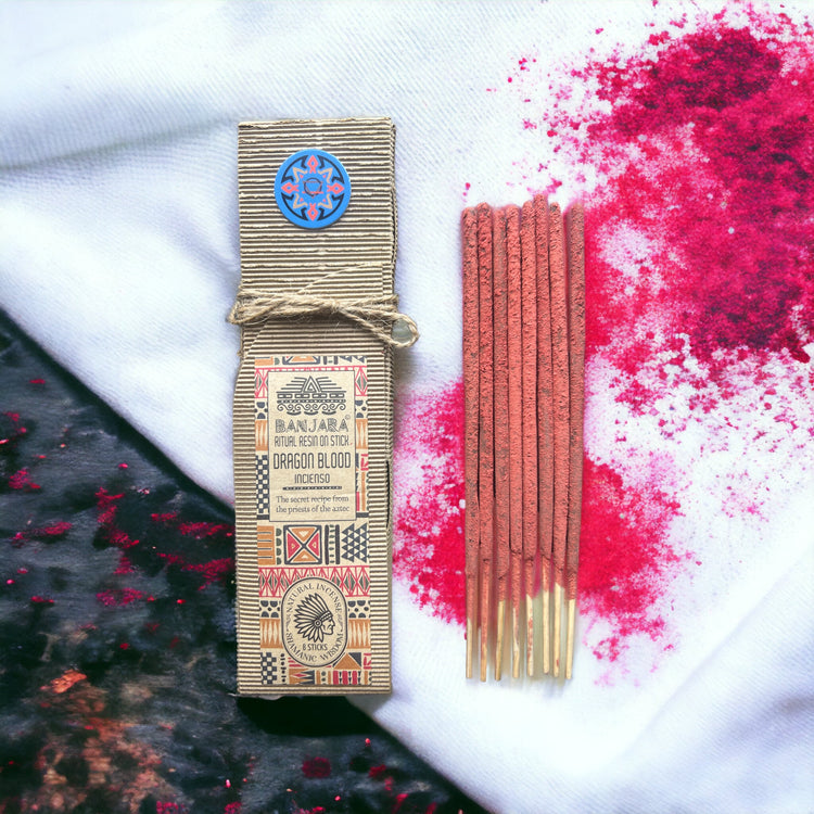 A pack of Dragon blood incense sticks displayed on a stone surface surrounded by various small plants, with a decorative box in the background.Underground Allure Essex, UK