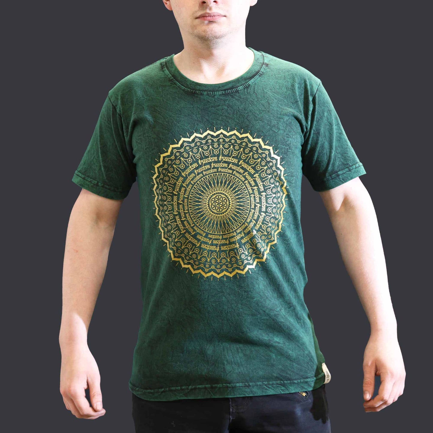 Person wearing a green t-shirt with a gold mandala design on a dark background