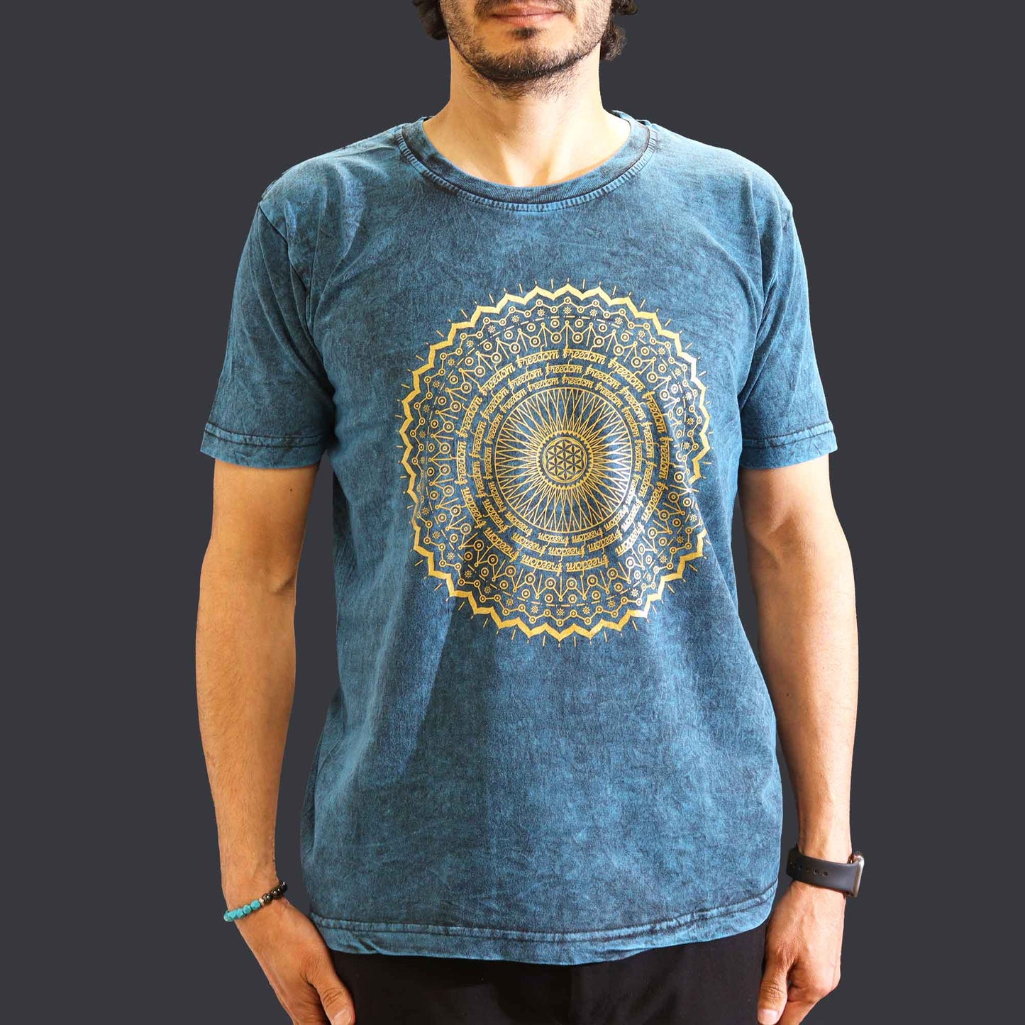 Person wearing a blue t-shirt with a gold mandala design on a dark background