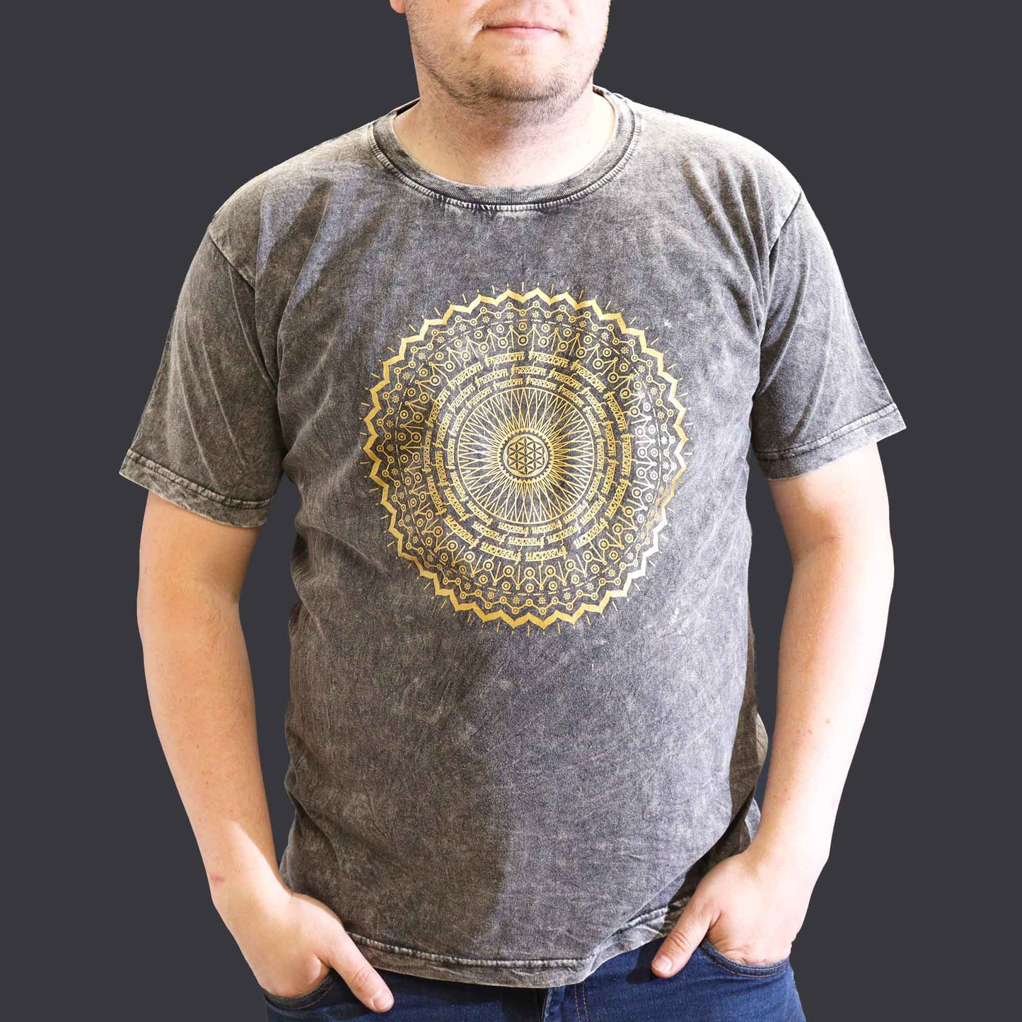 Person wearing a gray t-shirt with a gold mandala design on a plain background