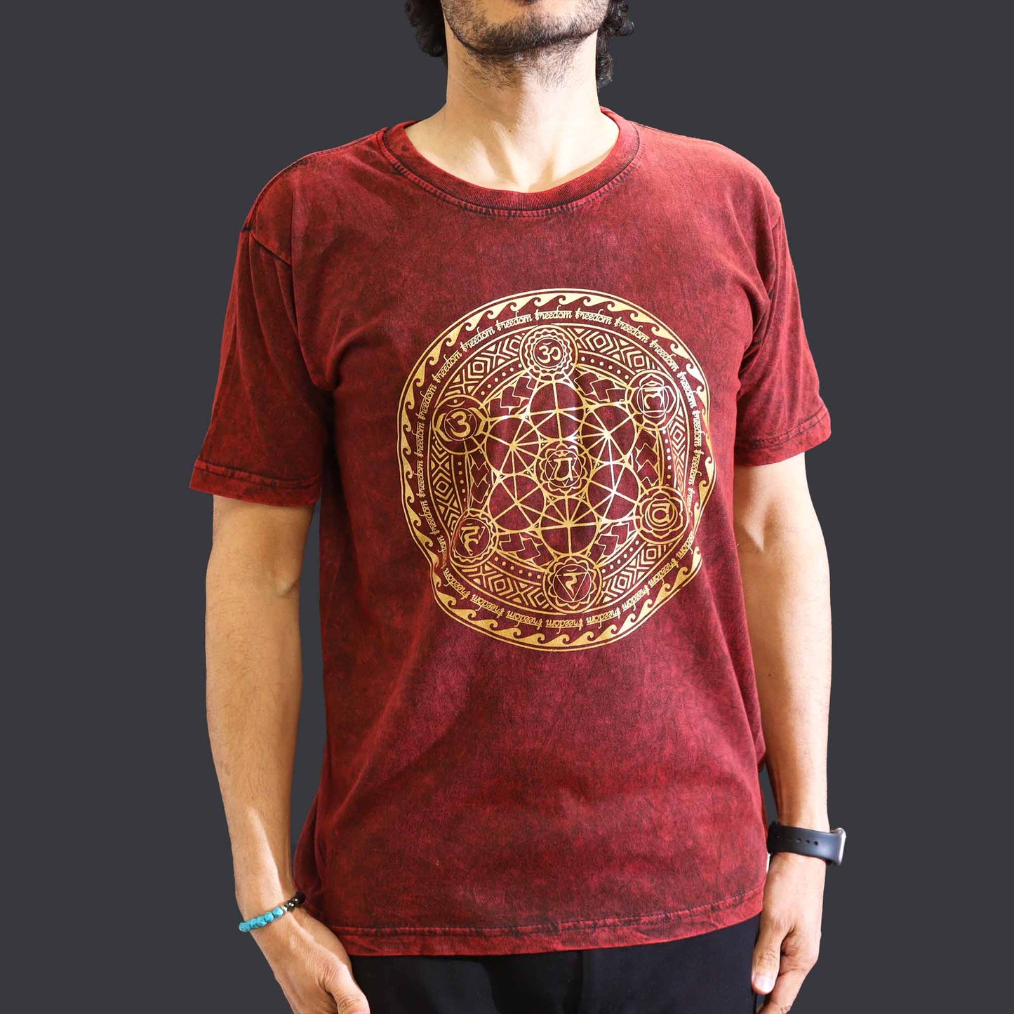 Red t-shirt with gold geometric design worn by a person on a dark background