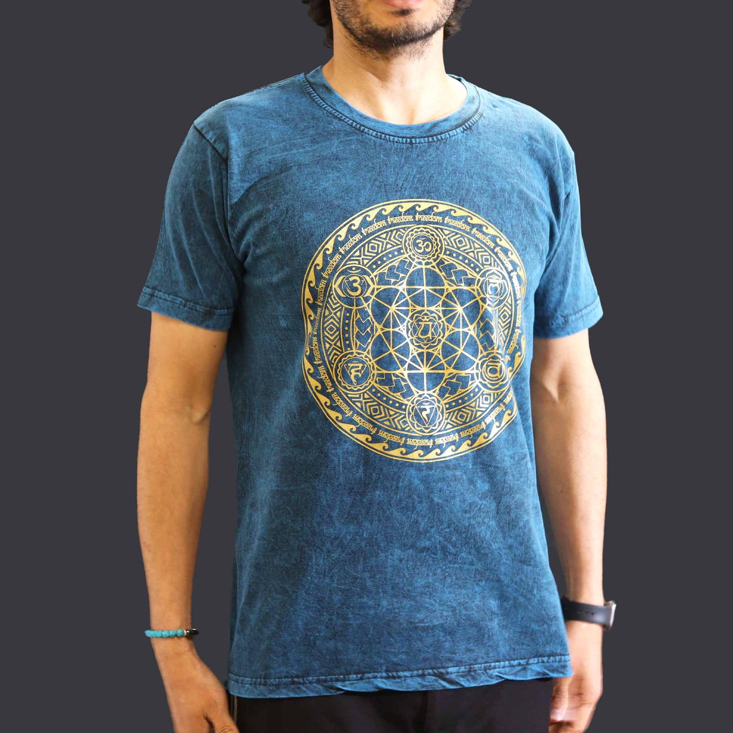 Person wearing a blue t-shirt with a gold geometric Chakra design on a dark background