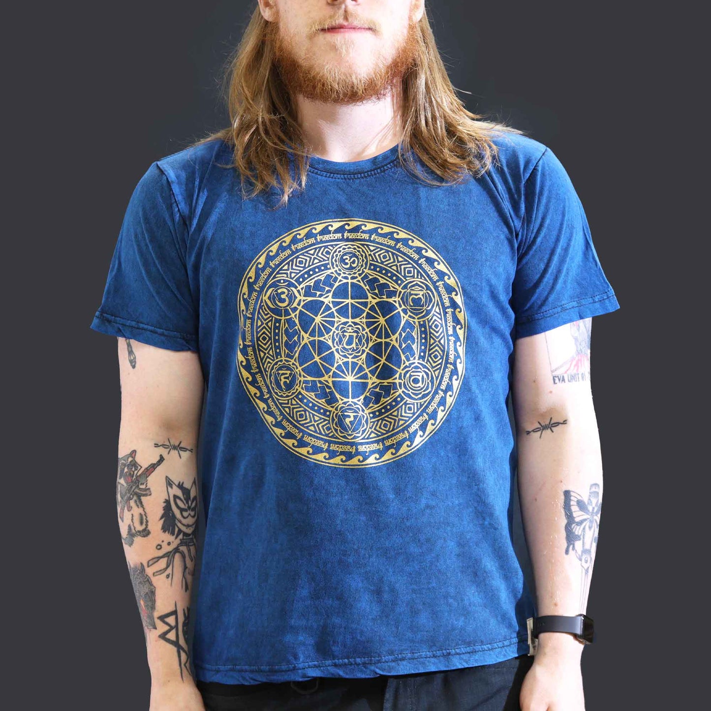 Person wearing a blue t-shirt with a gold geometric design on a dark background