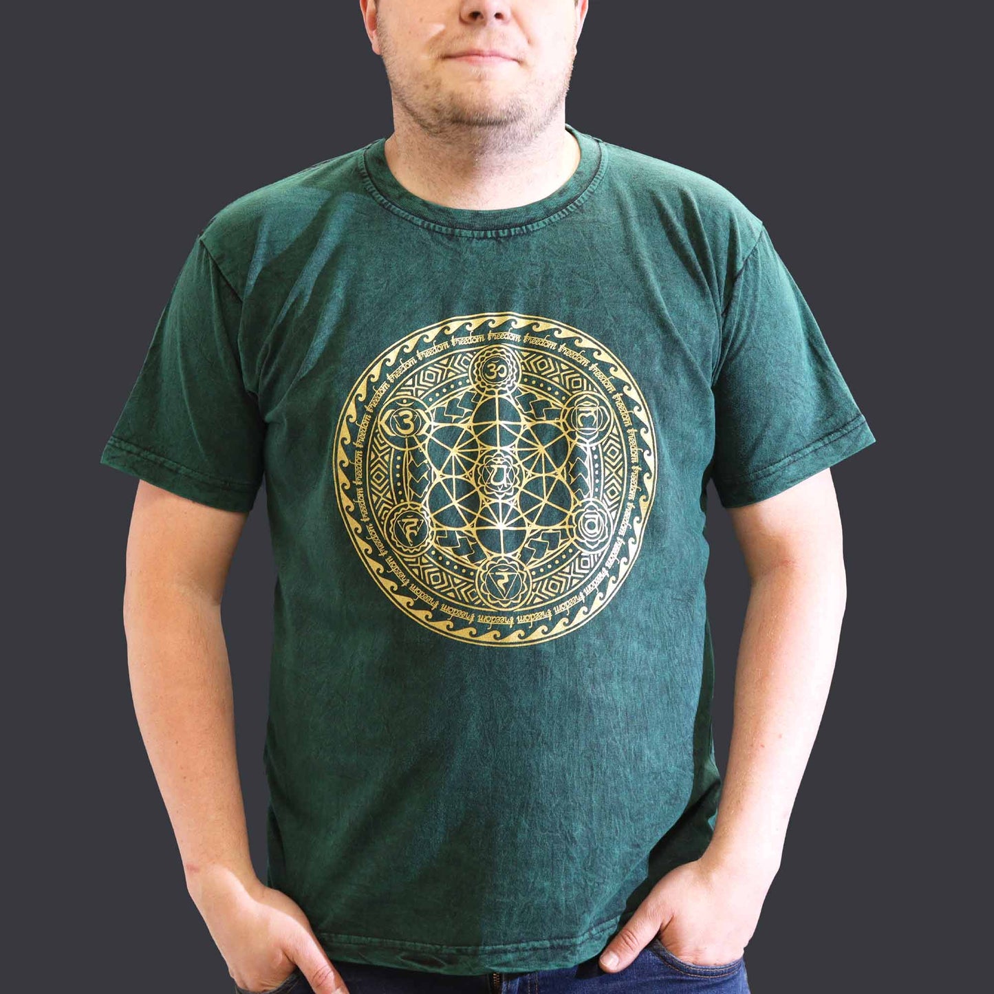 Person wearing a green t-shirt with a gold geometric design on a plain background