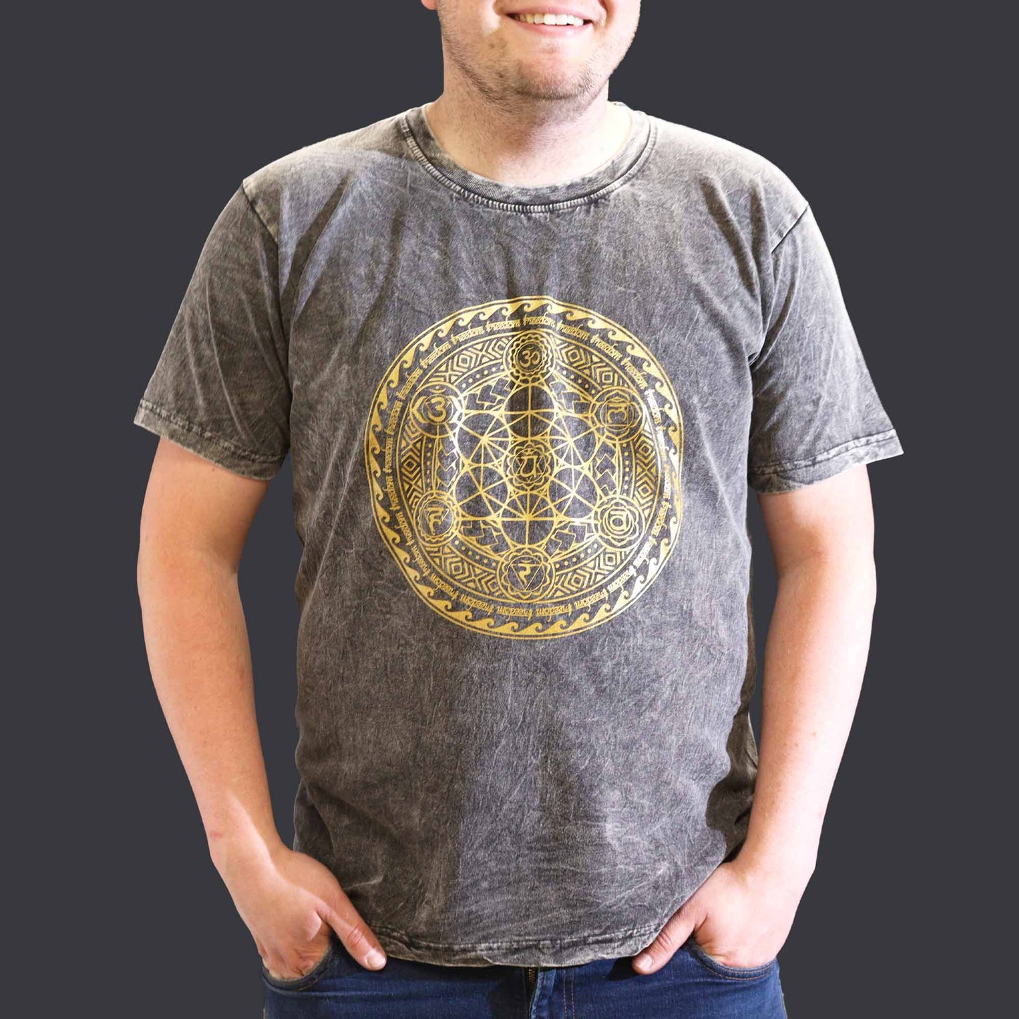 Person wearing a gray t-shirt with a gold geometric design on a plain background