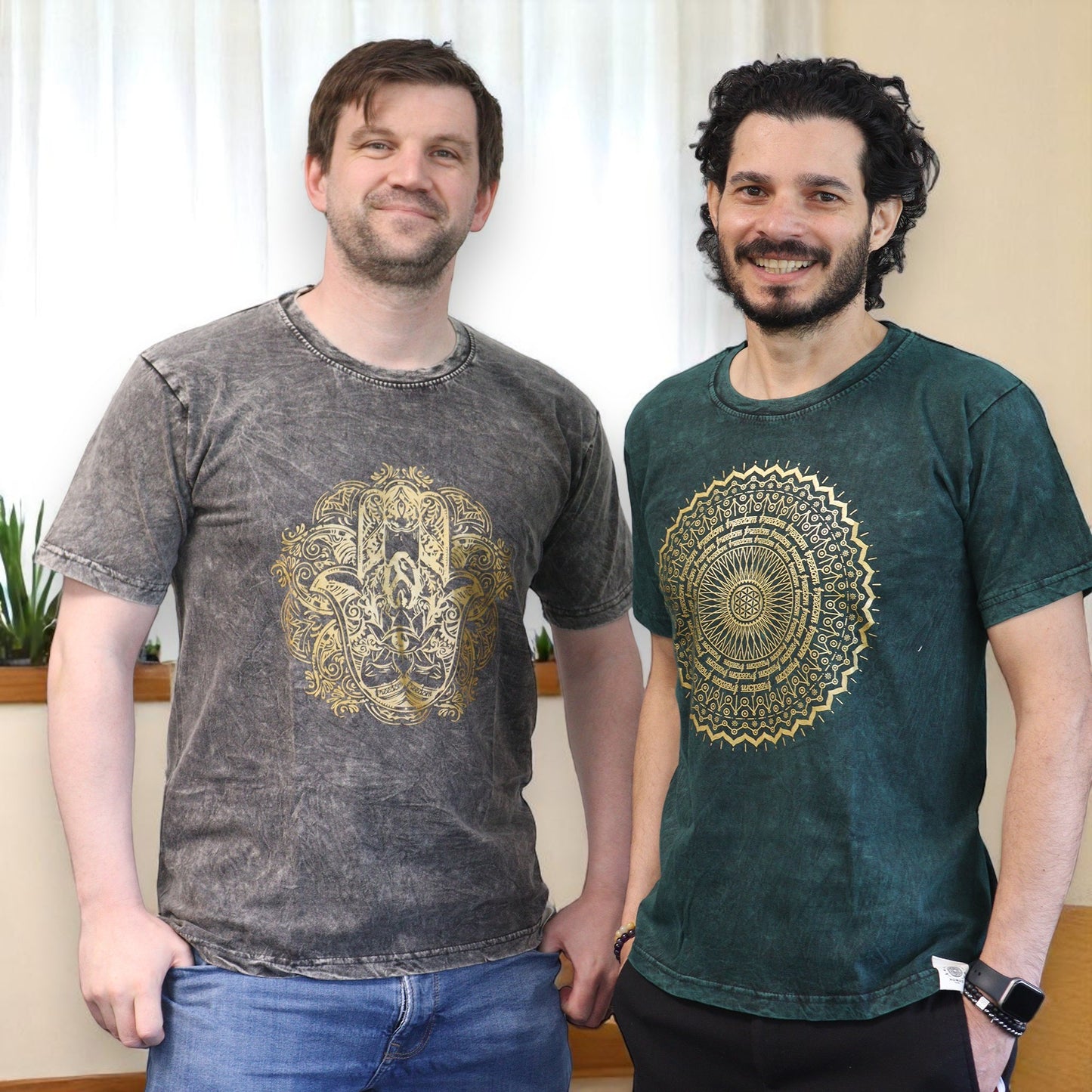 Two men wearing t-shirts with intricate designs standing indoors.