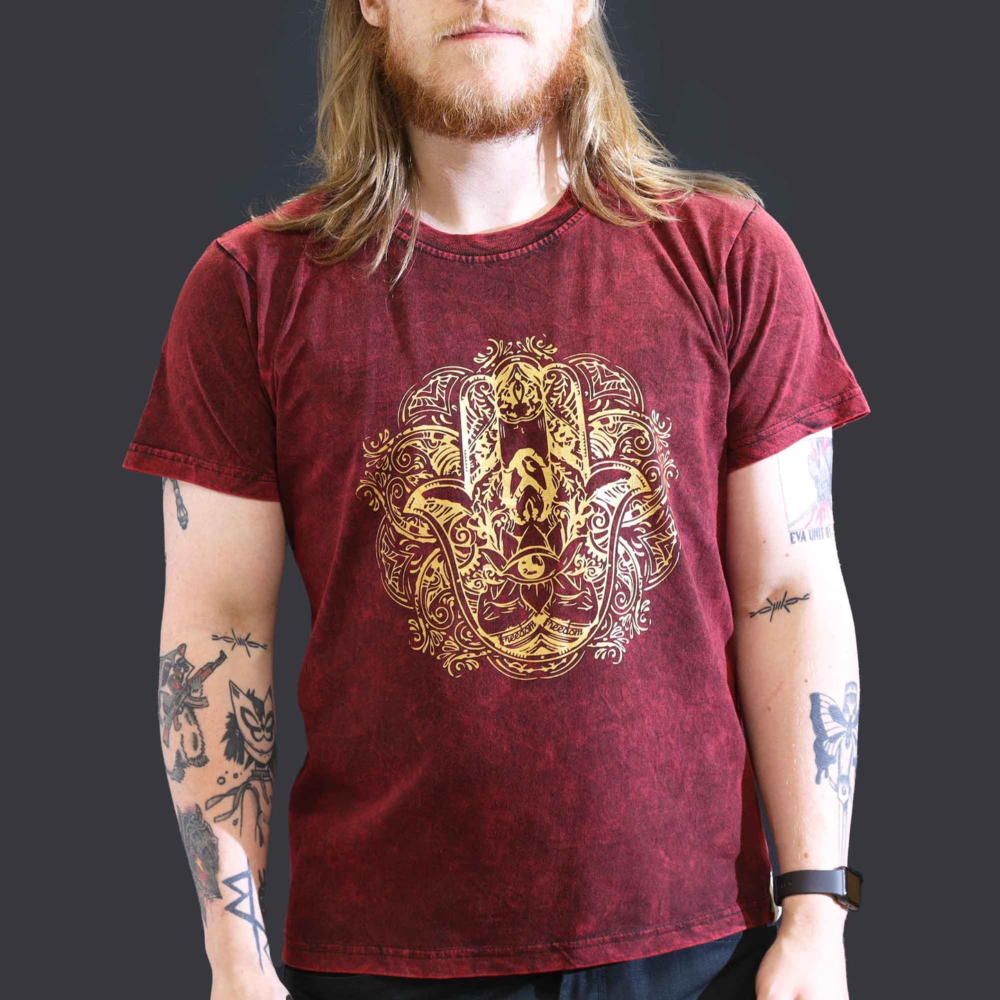 Person wearing a maroon t-shirt with a gold lion design on a dark background