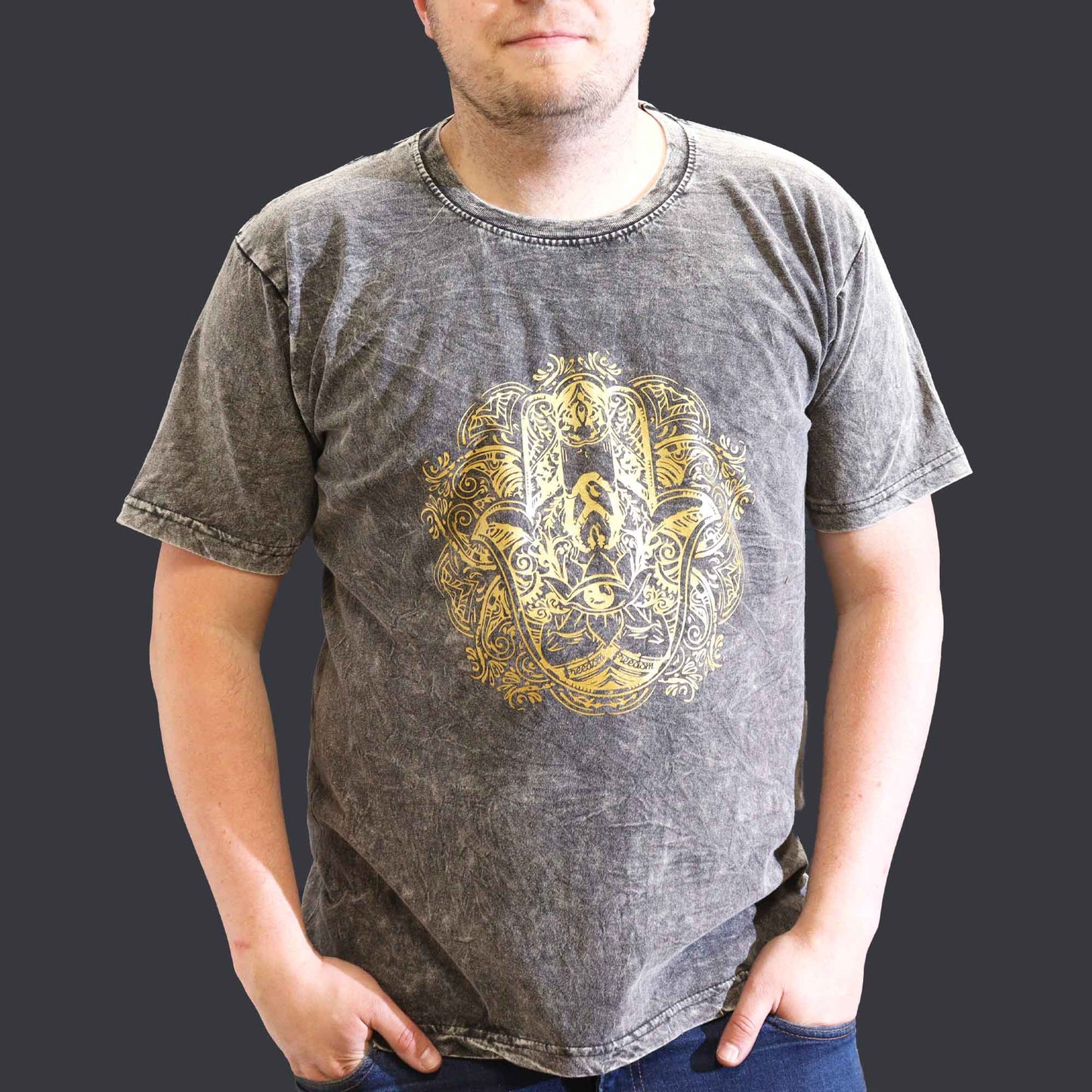 Person wearing a gray t-shirt with a gold Hamsa design on a dark background
