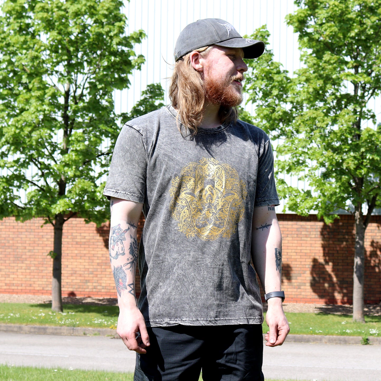 Man wearing a gray t-shirt with a gold Hamsa design outdoors