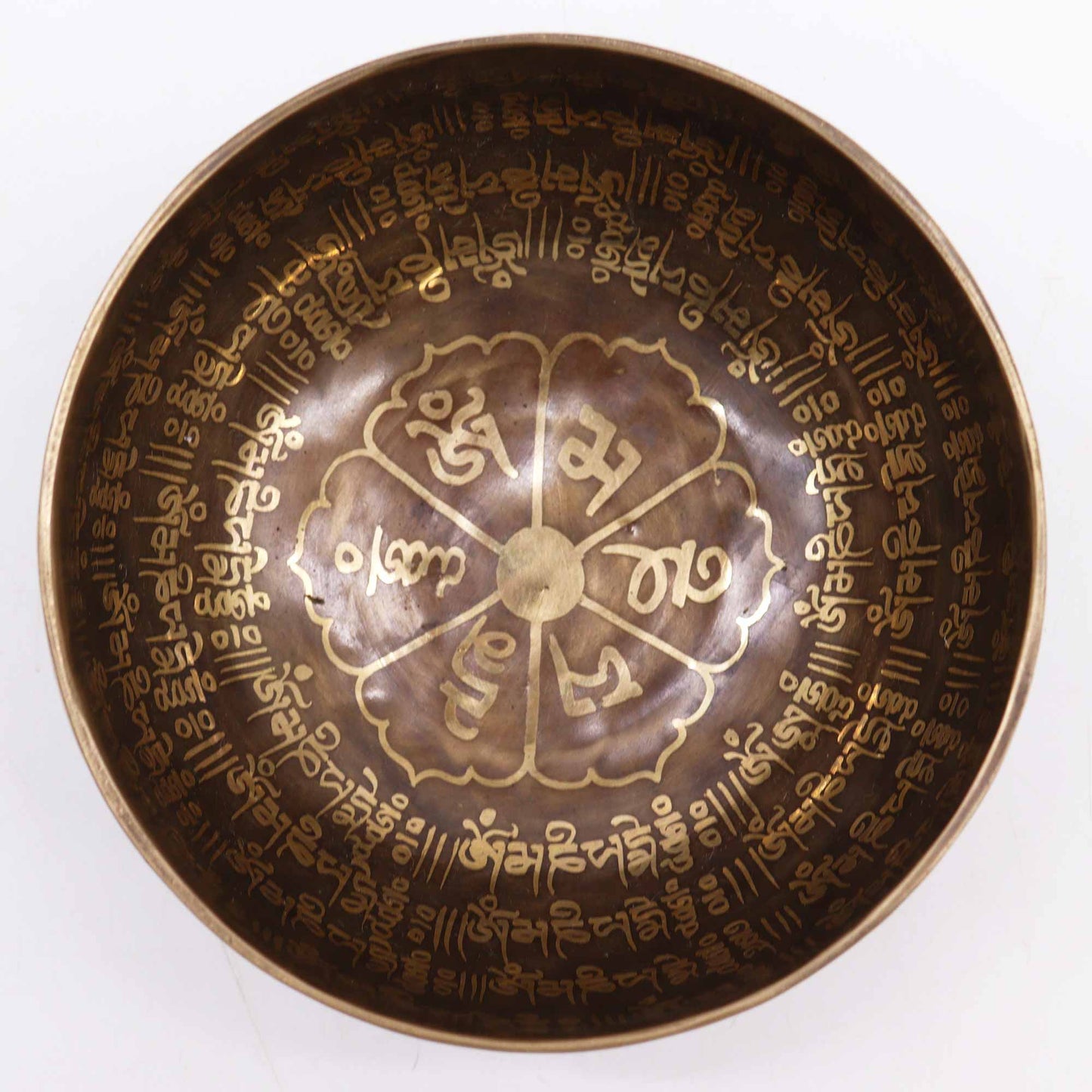 An engraved Tibetan singing bowl with intricate designs and symbols representing the 7 chakras, predominantly in a bronze or brown color.Underground Allure Essex, UK