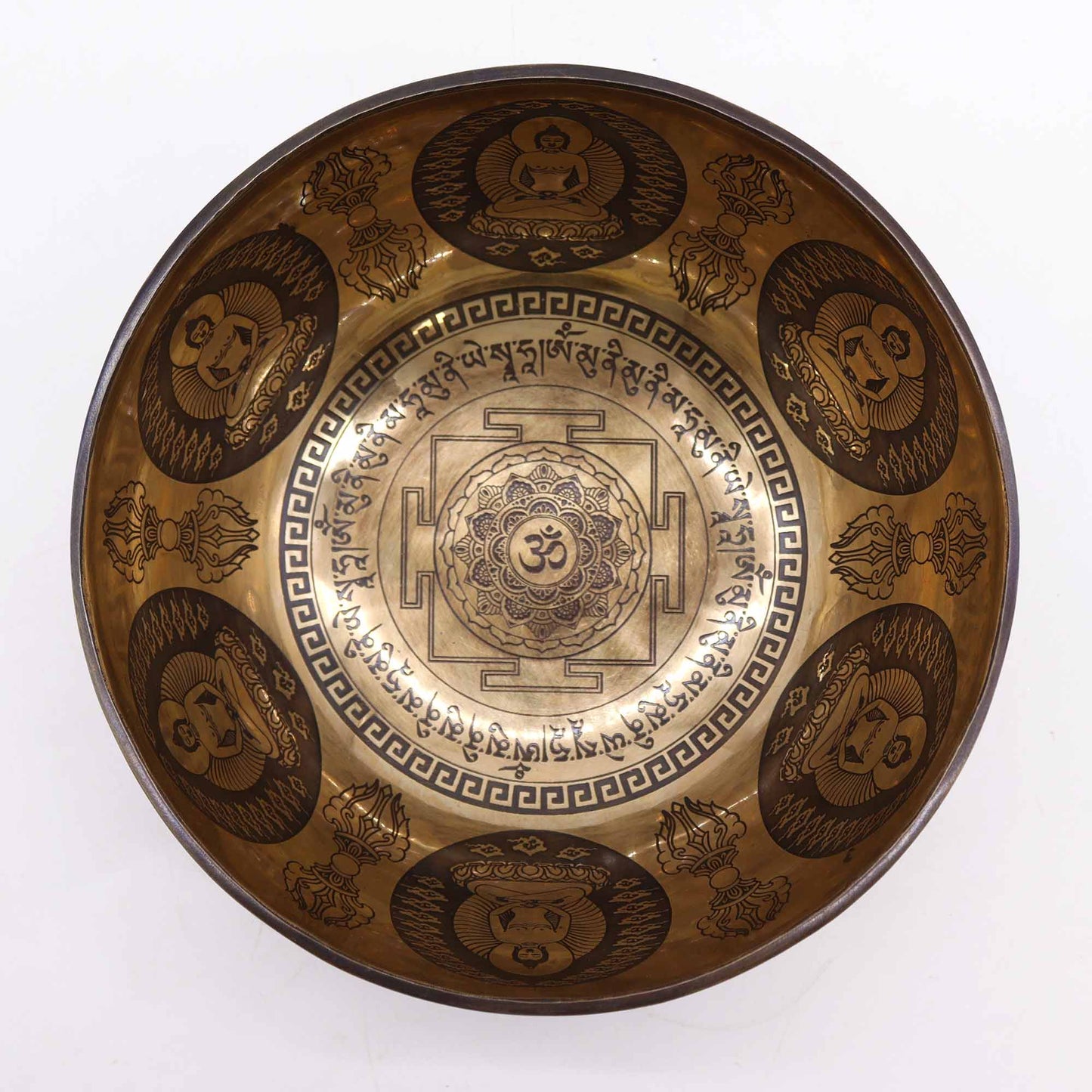 An engraved Tibetan singing bowl with intricate designs and symbols representing the 7 chakras, predominantly in a bronze or brown color.Underground Allure Essex, UK