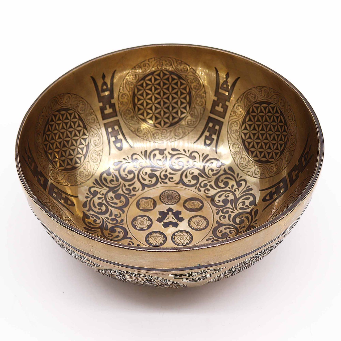 An engraved Tibetan singing bowl with intricate designs and symbols representing the 7 chakras, predominantly in a bronze or brown color. underground Allure Essex Uk