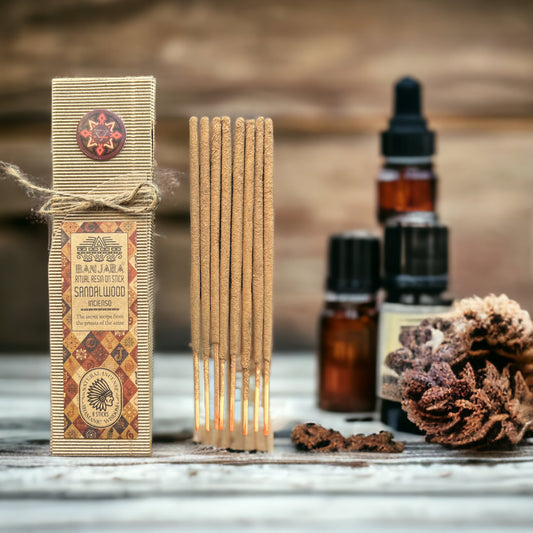 Sandalwood incense sticks with packaging and essential oil bottles on a wooden surface.