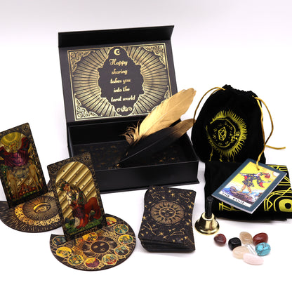 Collection of tarot cards, a black box, A bell and stones and a card holders, a 2 feathers, and guidebook, and other mystical items on a white background