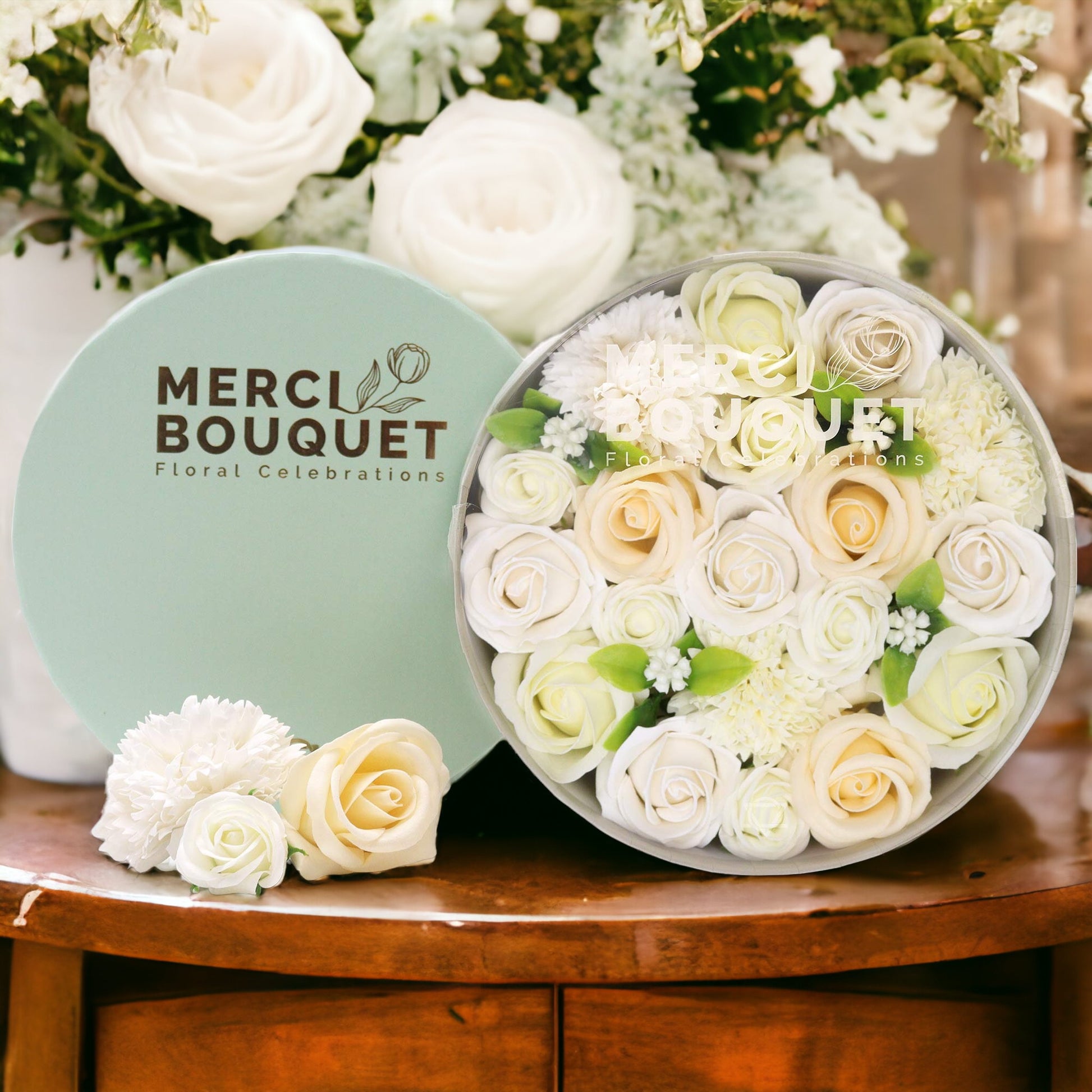 Floral arrangement in a box with 'Merci Bouquet' branding on a wooden table.