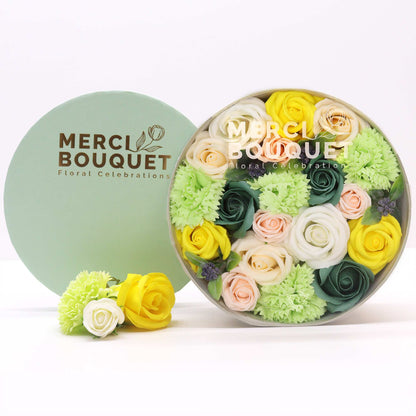 Round floral arrangement in a box with 'Merci Bouquet' branding on a white background
