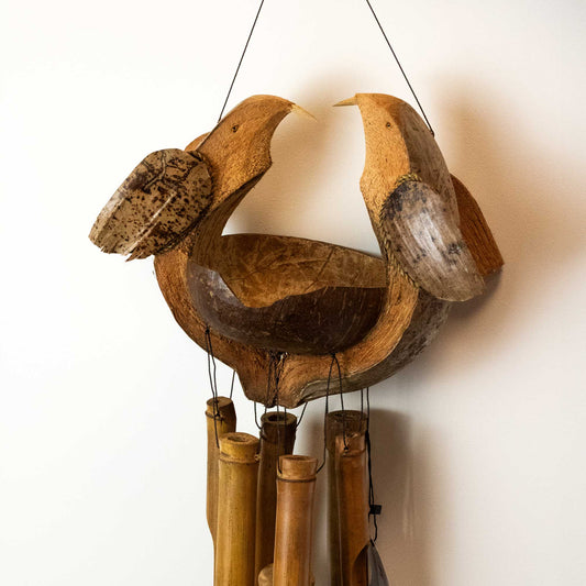 Wooden bird-shaped wind chime with bamboo tubes on a white background