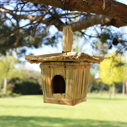 Wooden birdhouse hanging from a tree branch with a blurred natural background