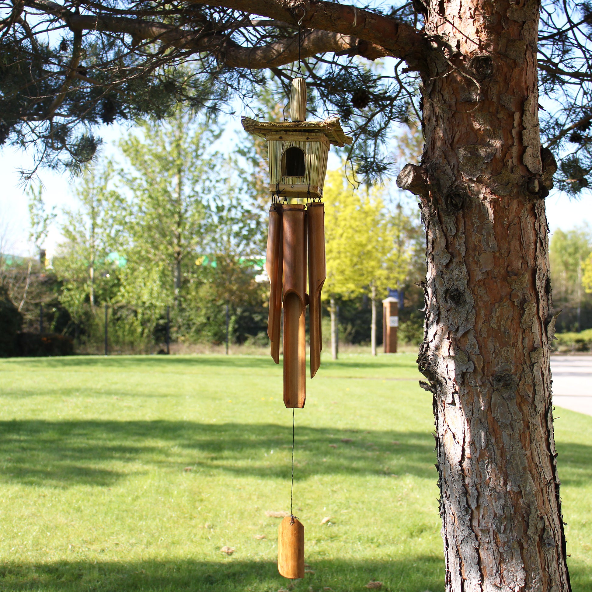 Wooden wind chime hanging from a tree in a park setting