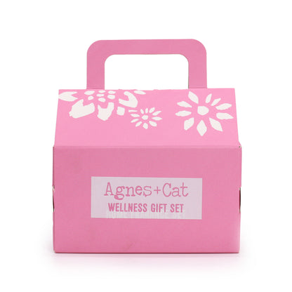 Pink gift box with white floral designs and 'Agnes + Cat Wellness Gift Set' label on a white background