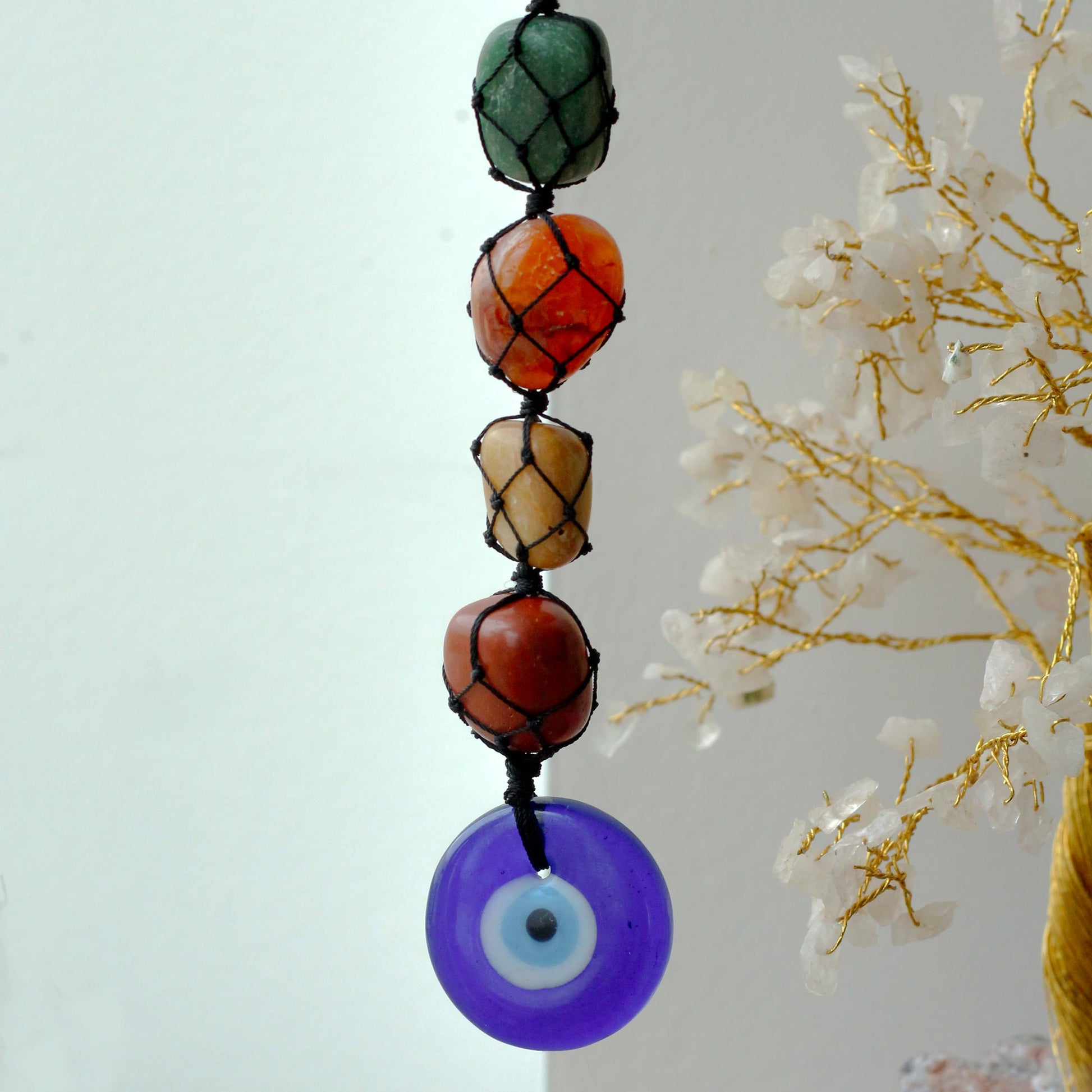 Hanging Chakra Stone Pendant - Evil Eye with a blue evil eye pendant against a light background