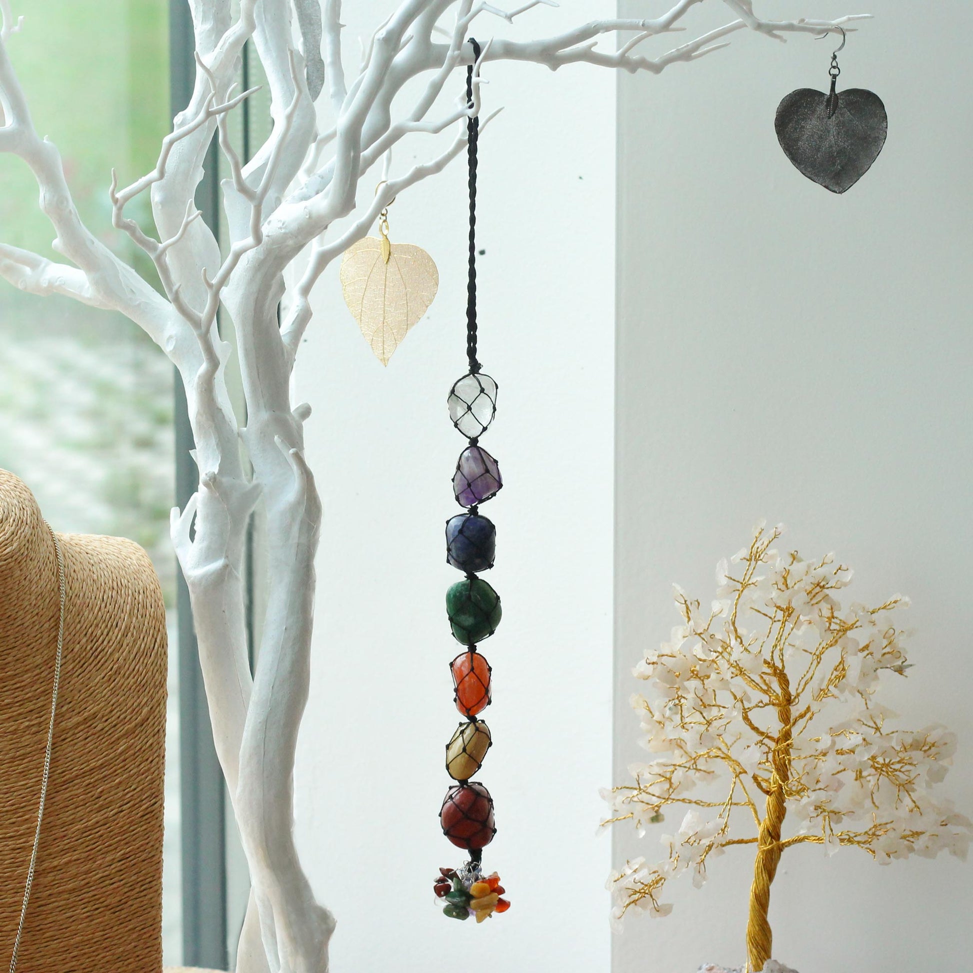 Hanging Chakra Stone Pendant - Seven Chakra Chips and a heart-shaped object on a white branch.