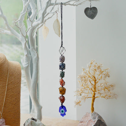 Hanging Chakra Stone Pendant - Hansa on a white branch.