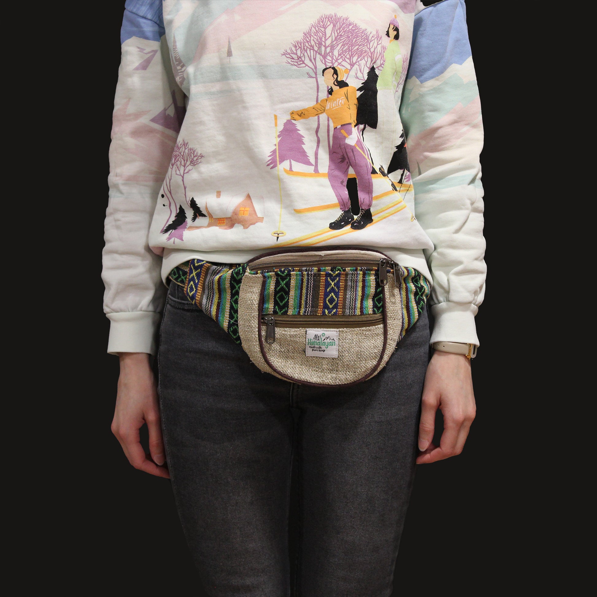 Person wearing a colorful sweater with a nature-themed design and a patterned fanny pack.
