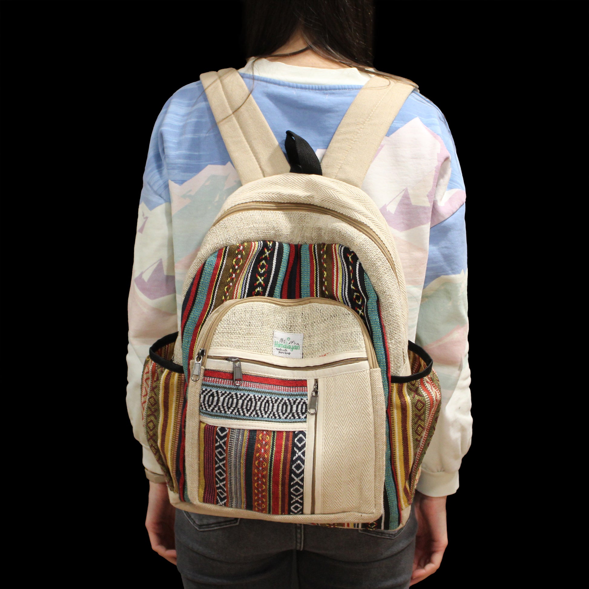Person wearing a beige backpack with colorful patterns on a black background