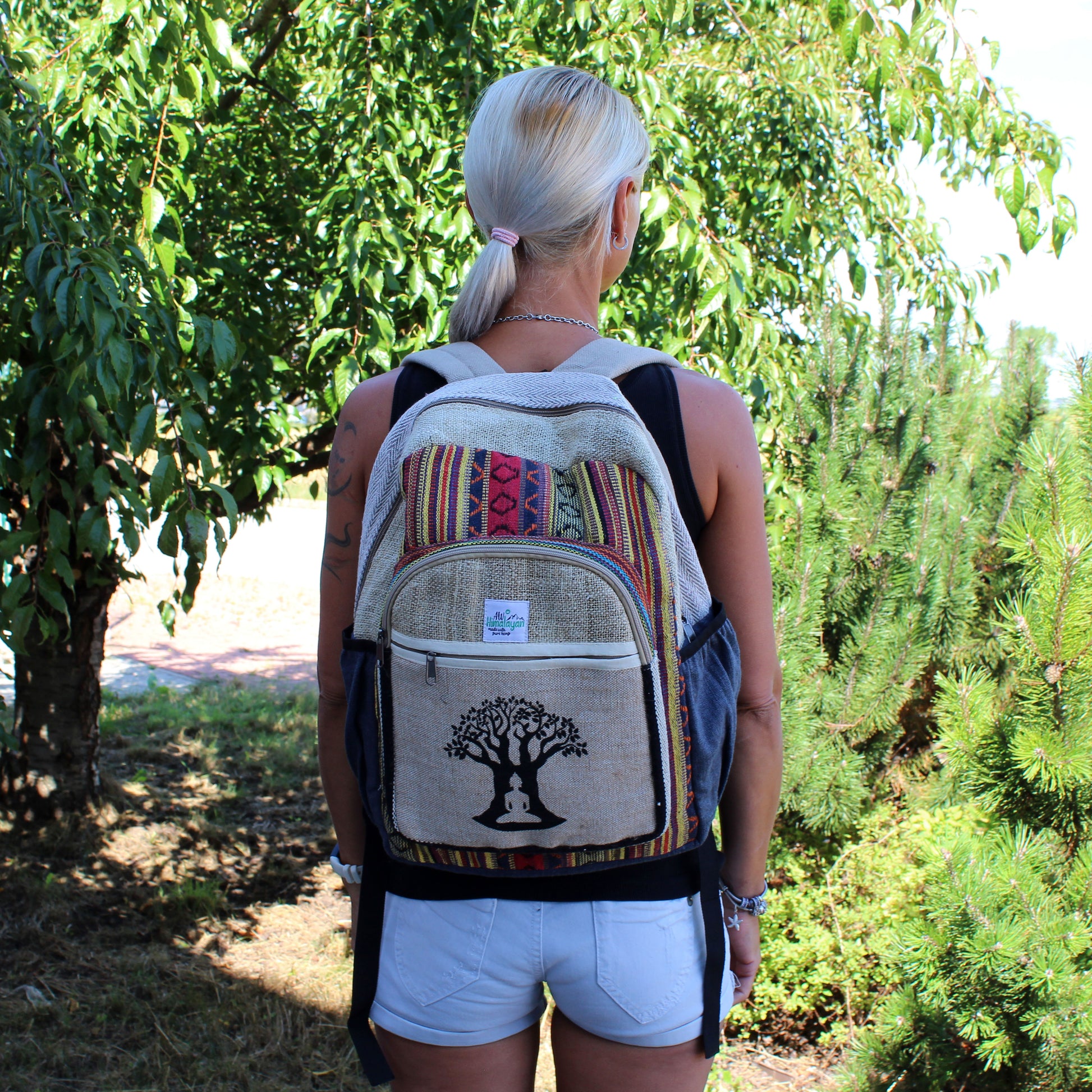Person wearing a backpack with a tree design in a forest setting