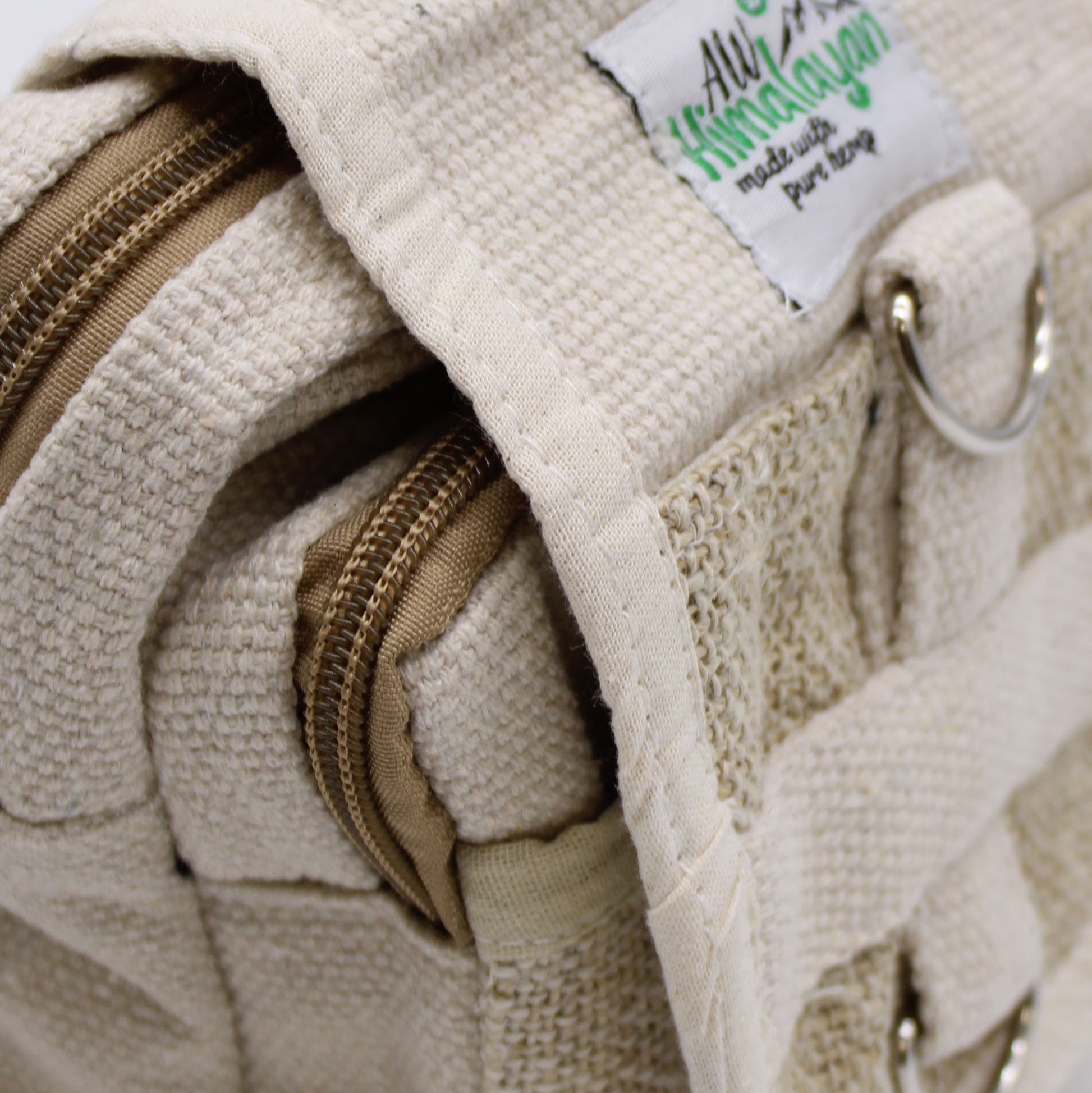 Close-up of a beige textured bag with a zipper and a visible brand tag.