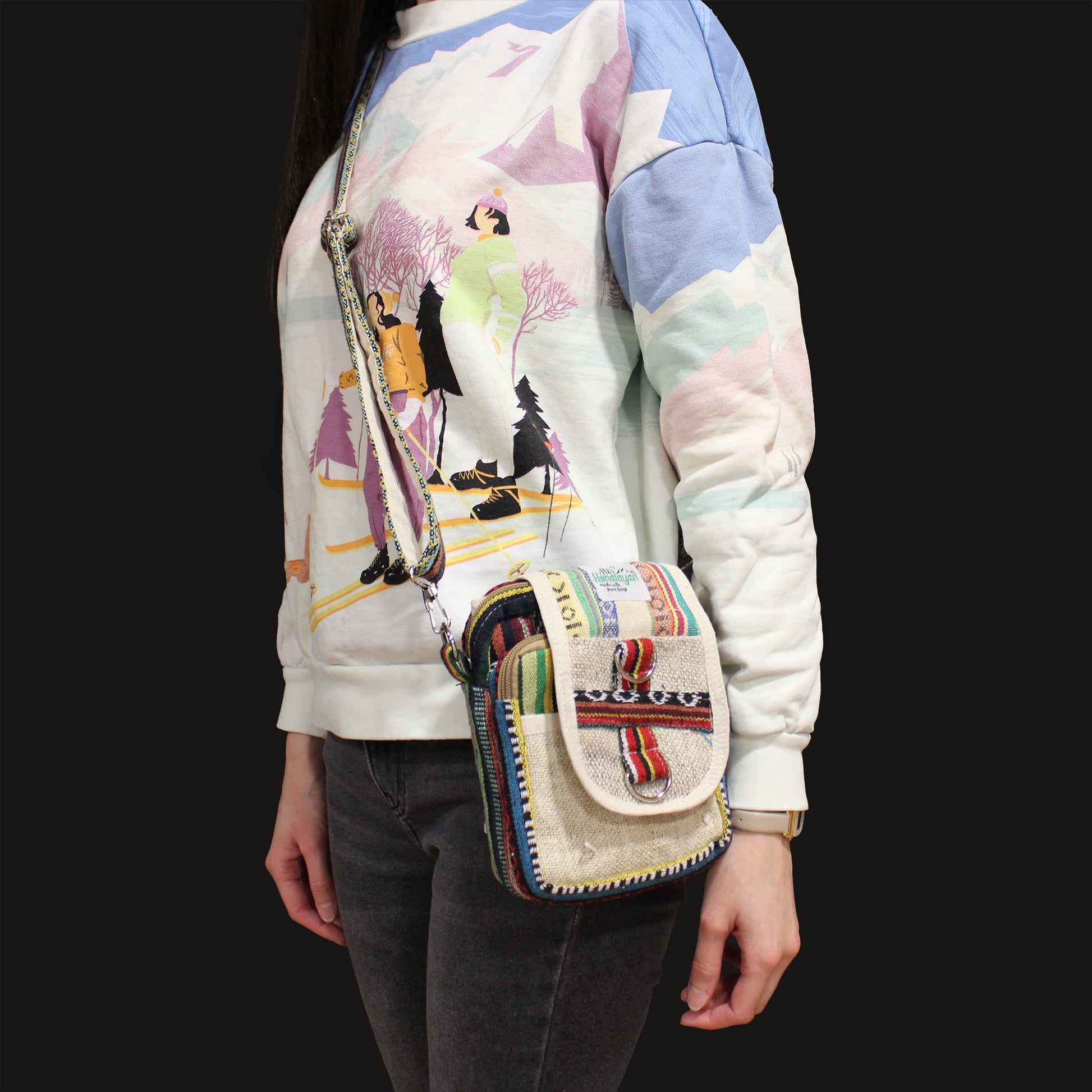 Person wearing a colorful jacket with a patterned bag over their shoulder on a black background