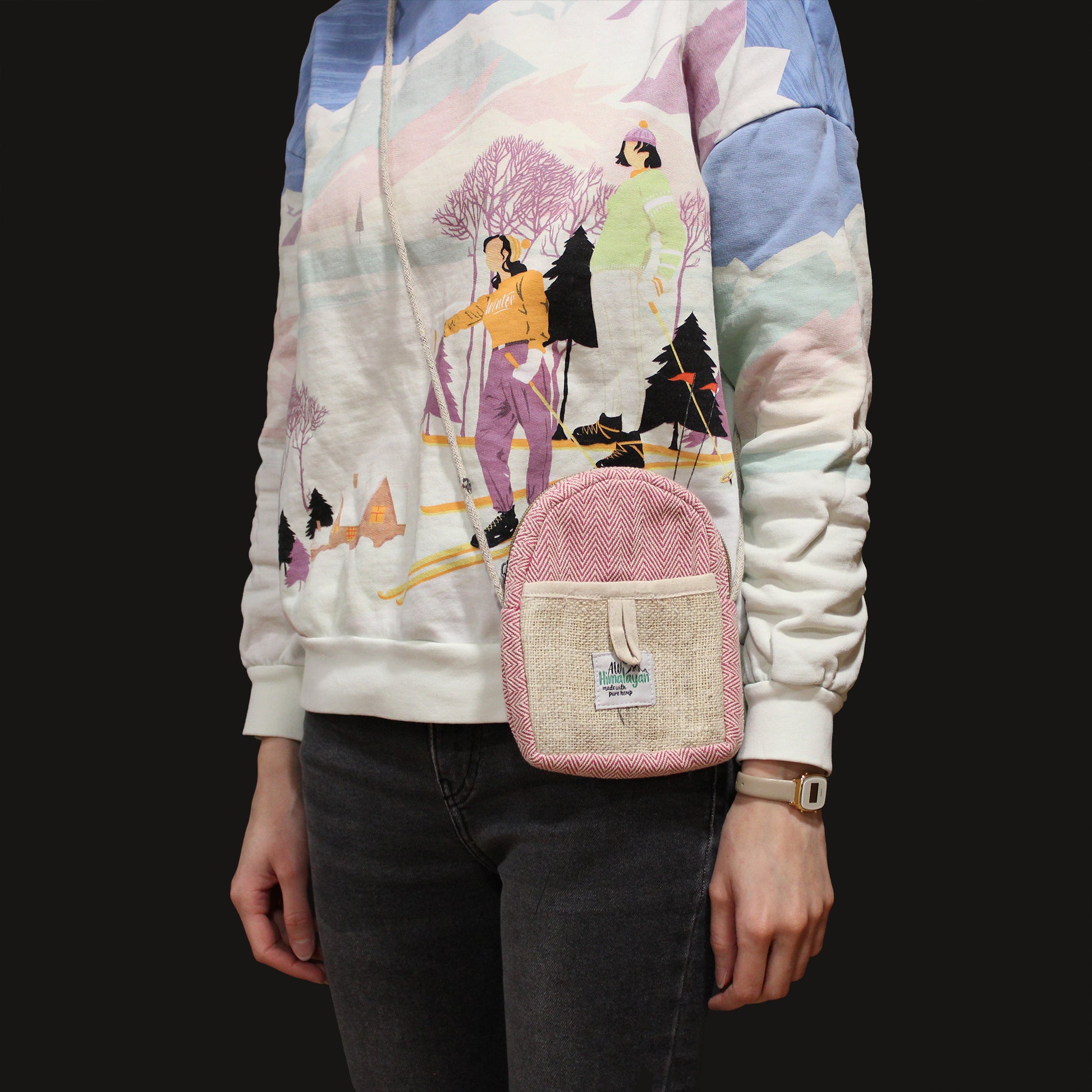 Person wearing a colorful hoodie with a graphic design, holding a pink backpack.