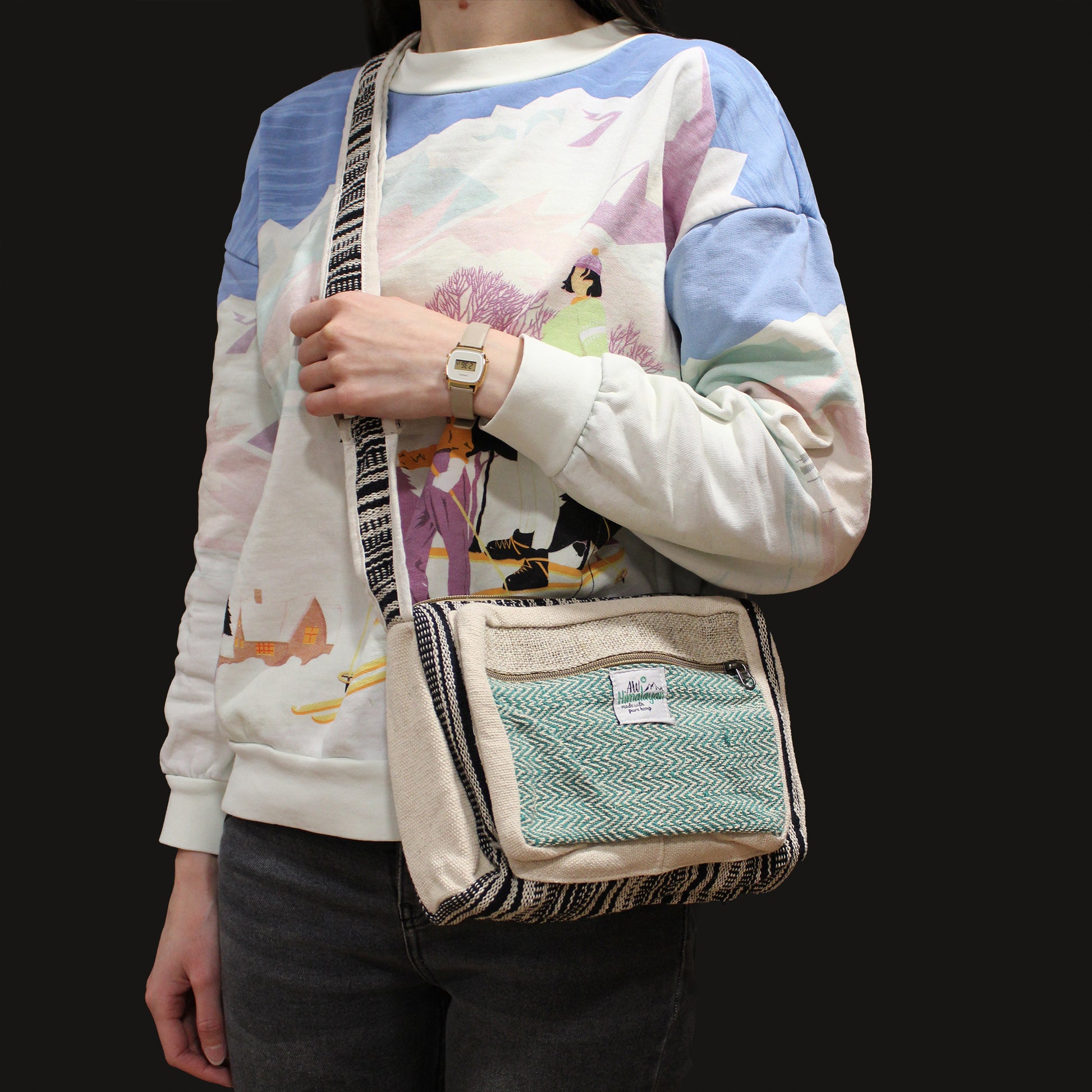 Person wearing a colorful sweater holding a textured crossbody bag with a black background