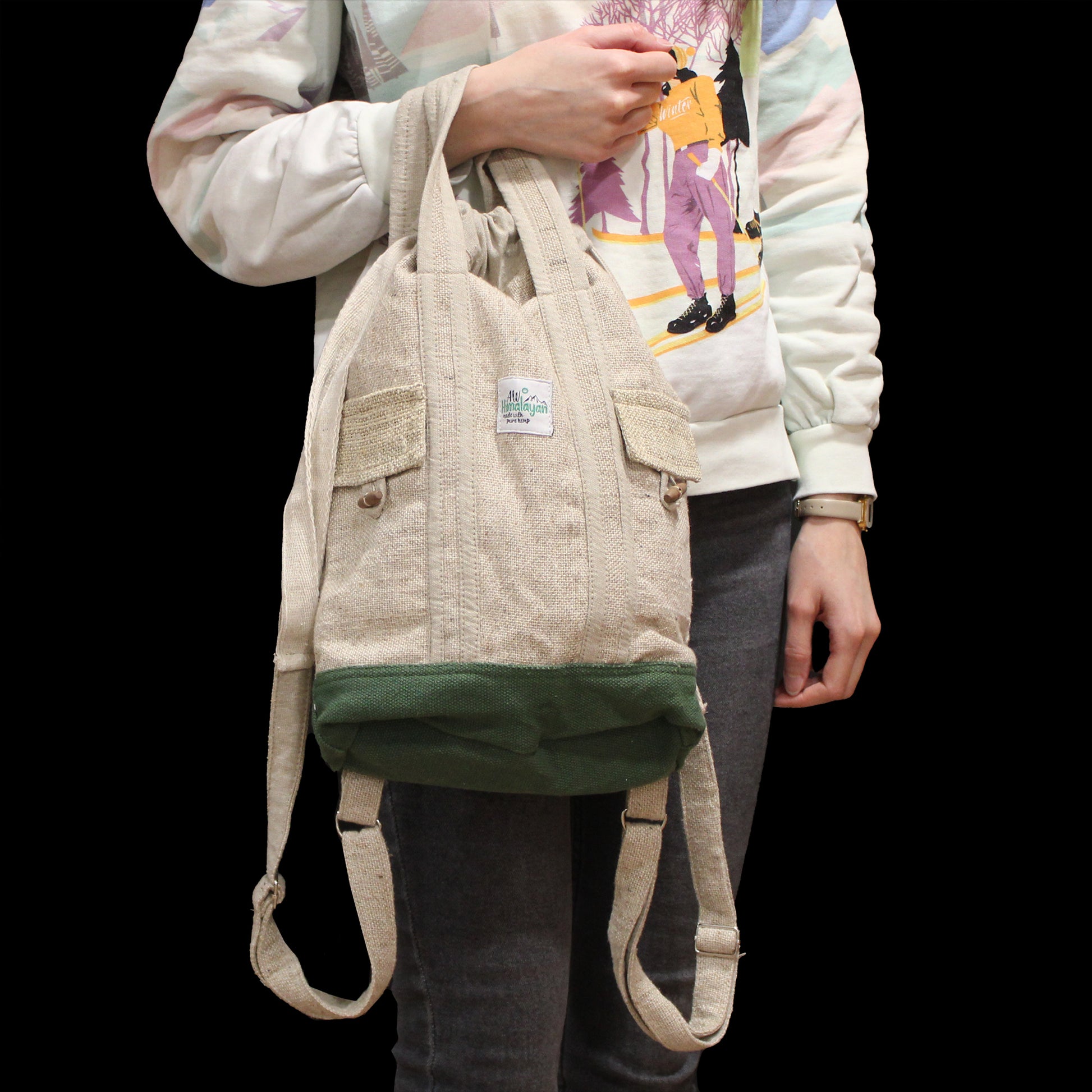 Person wearing a beige backpack with a visible brand logo on a black background
