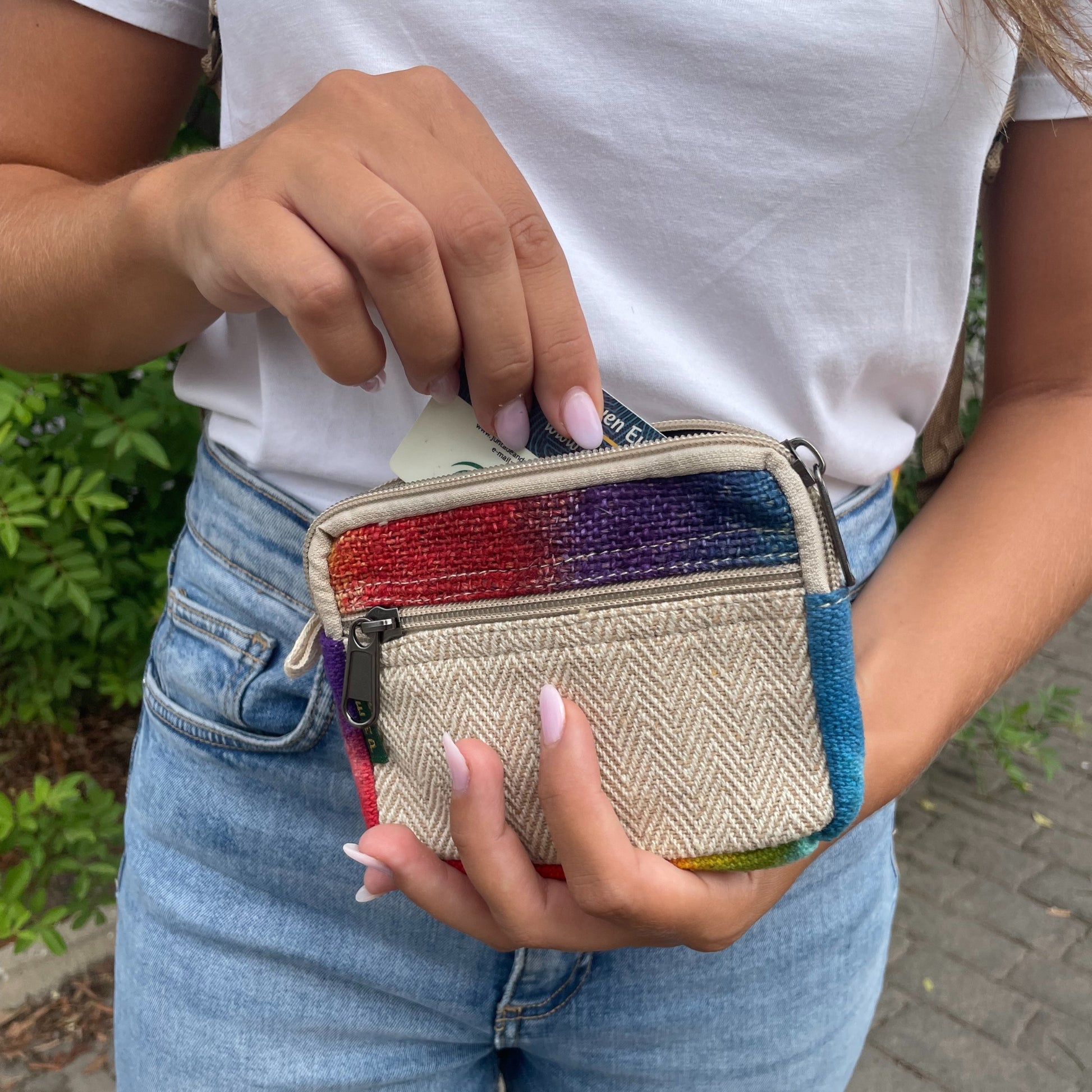 Person holding a colorful woven pouch with a blurred outdoor background