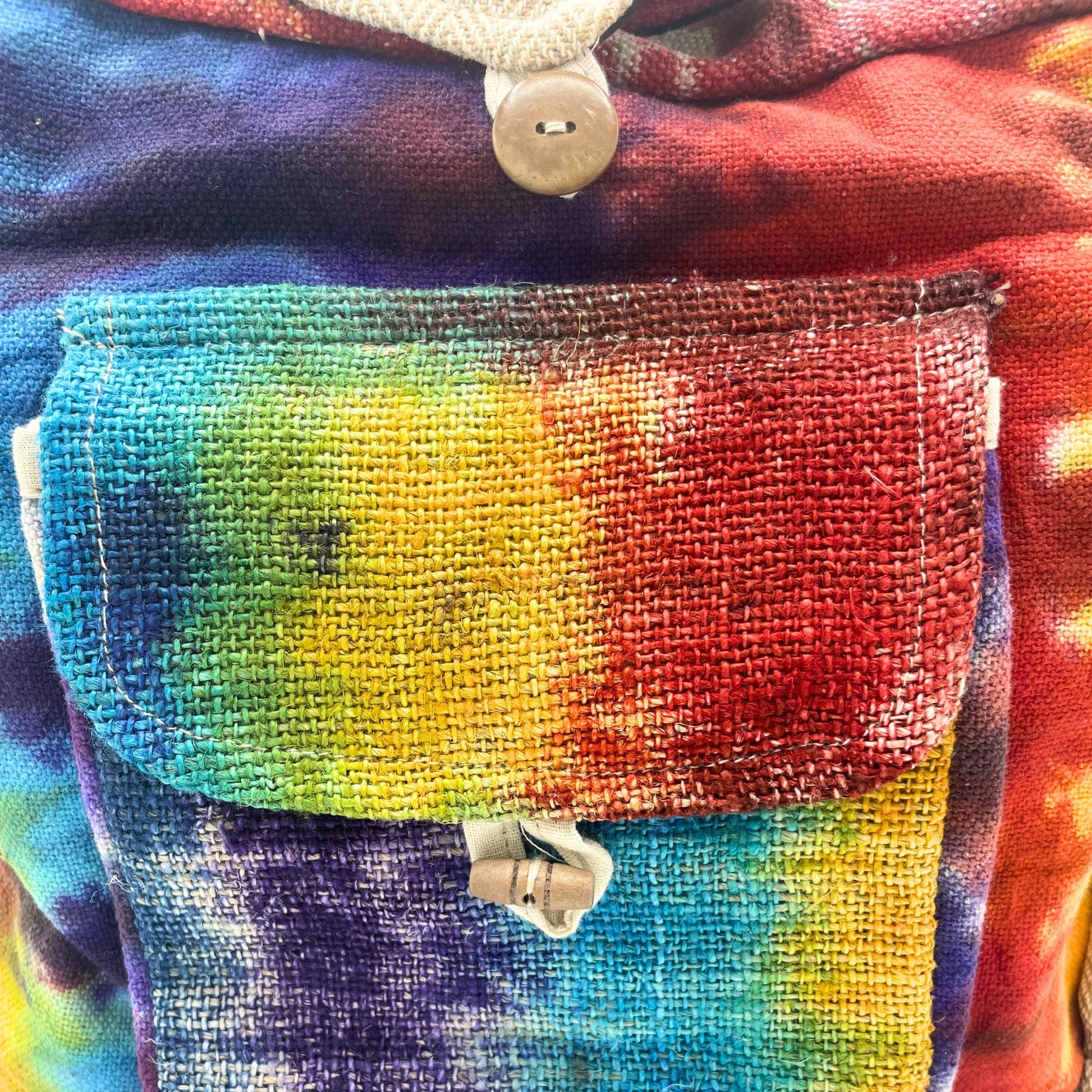Close-up of a colorful tie-dye fabric with a pocket and button details.