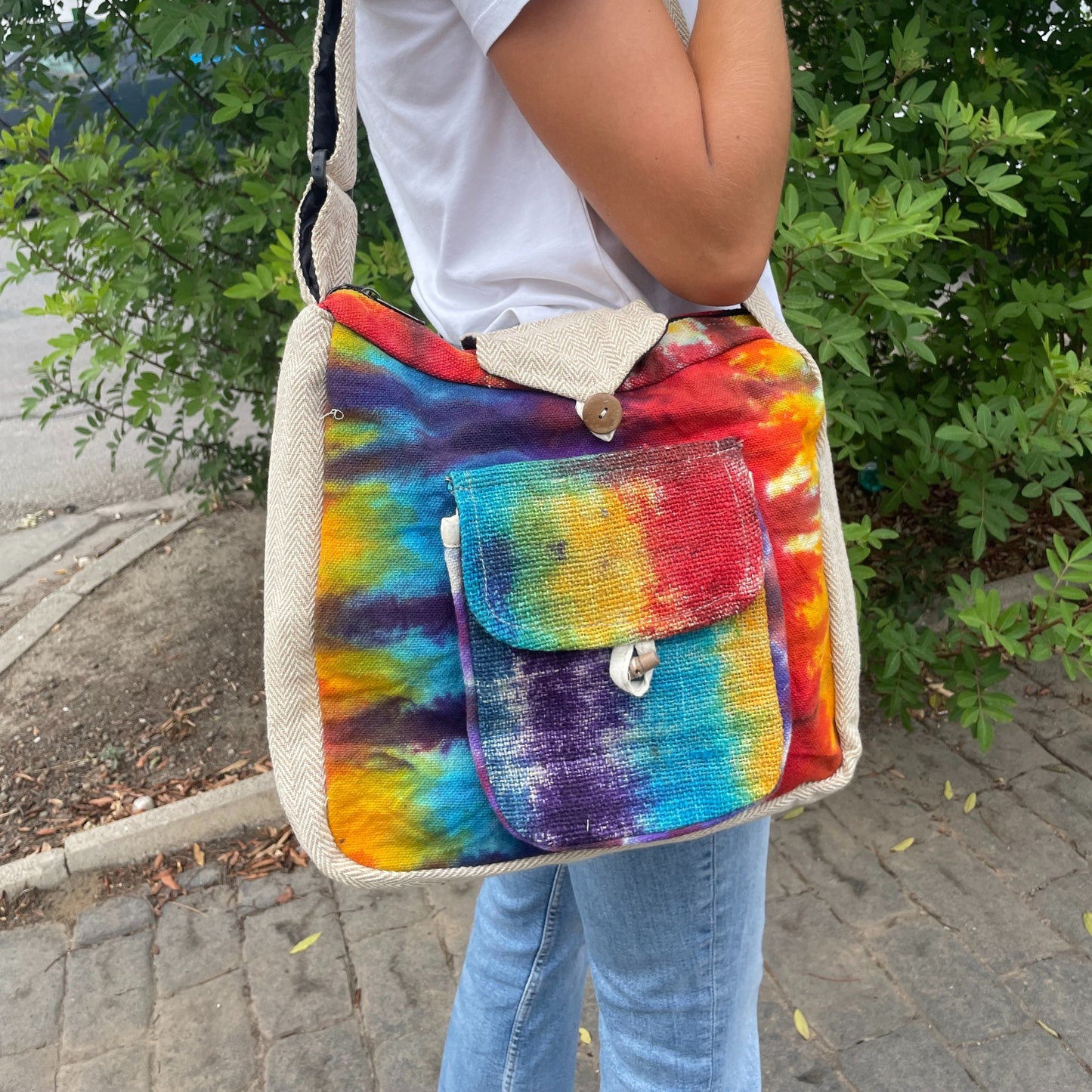 Person holding a colorful tie-dye bag with a natural material trim.