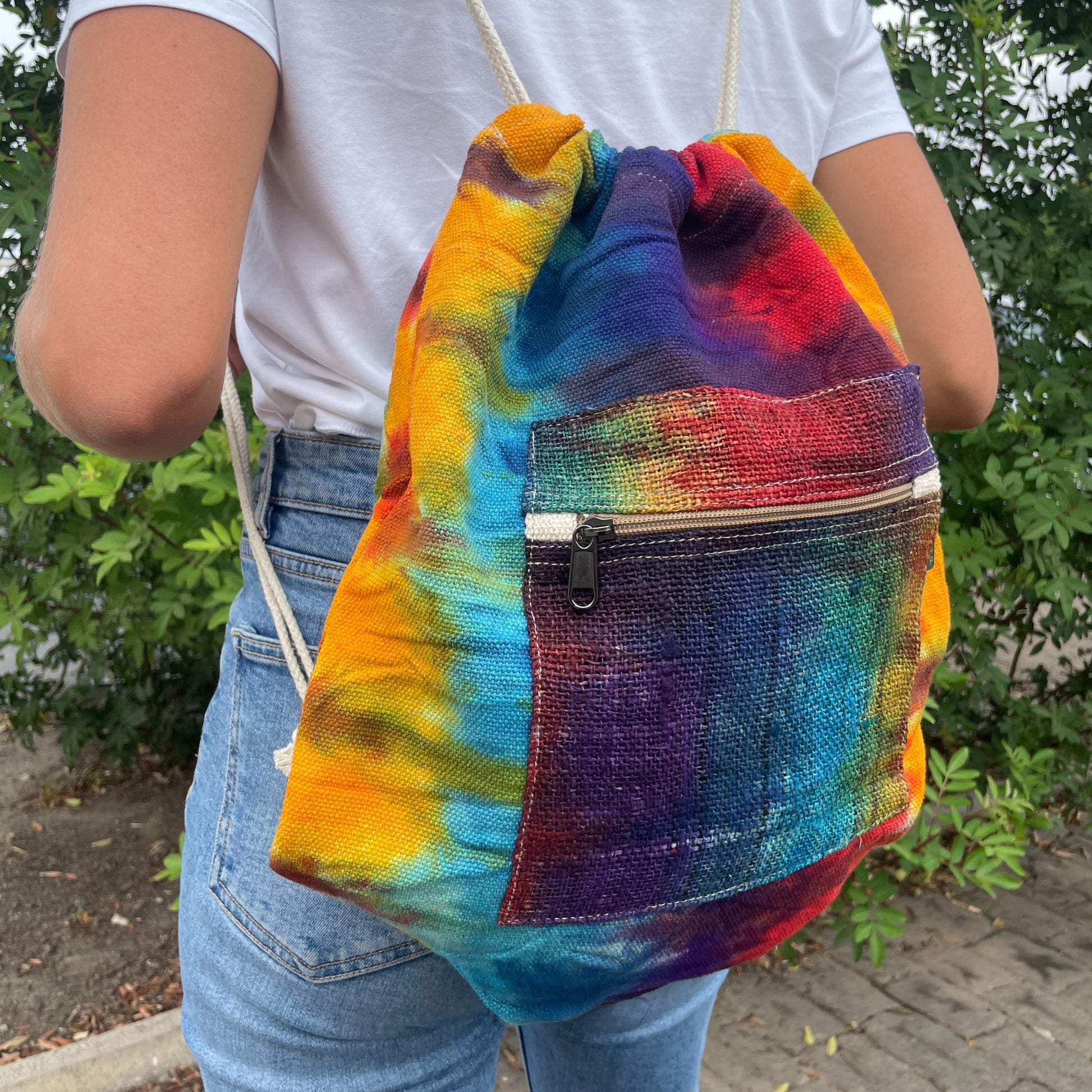 Person holding a tie-dye drawstring bag with a colorful pattern.