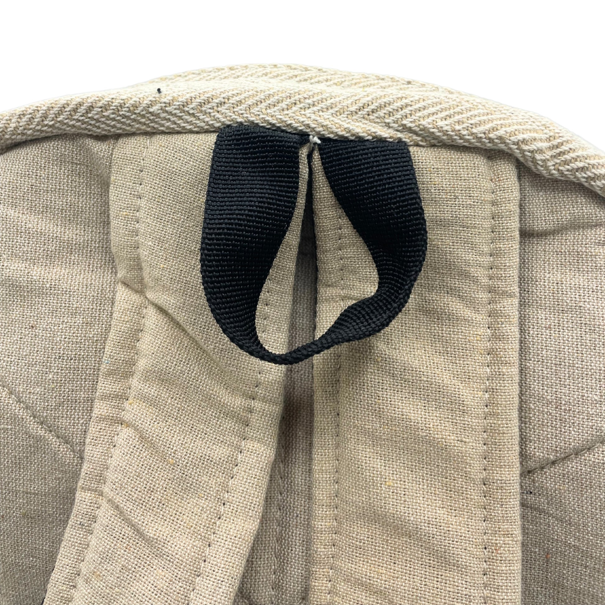 Close-up of a beige fabric bag with a black strap on a white background