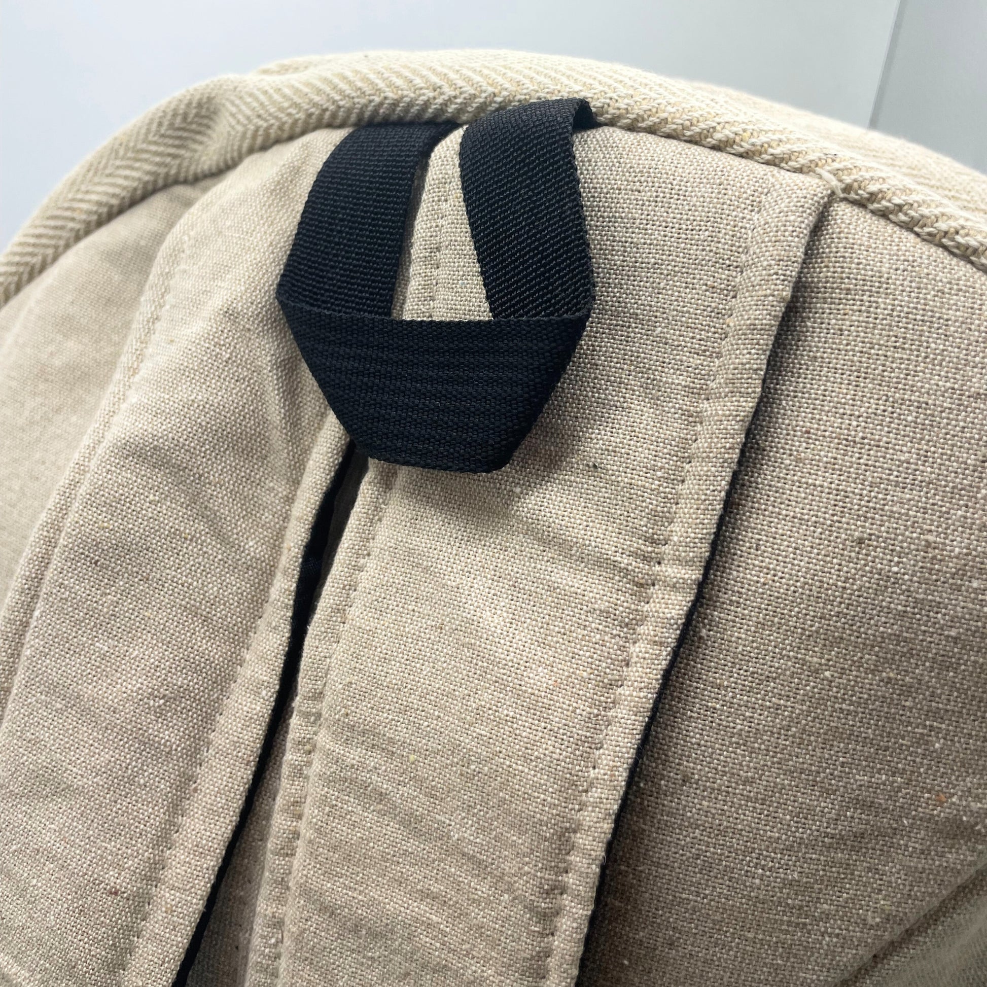 Close-up of a beige fabric bag with a black strap on a light gray background