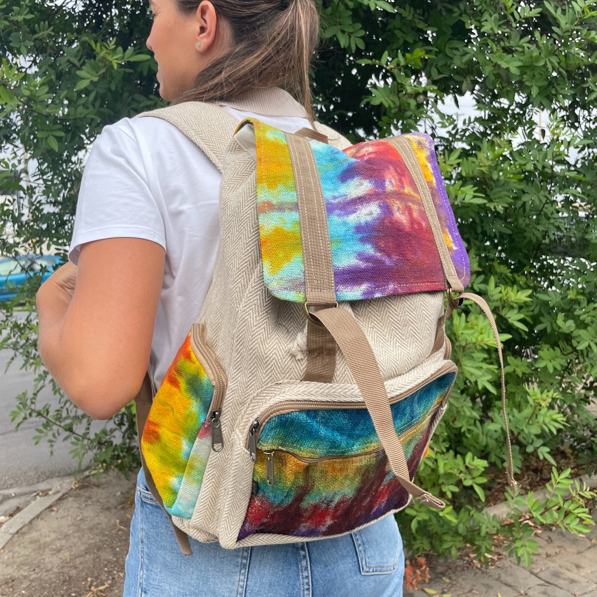 Person wearing a colorful tie-dye backpack with a natural bag base.