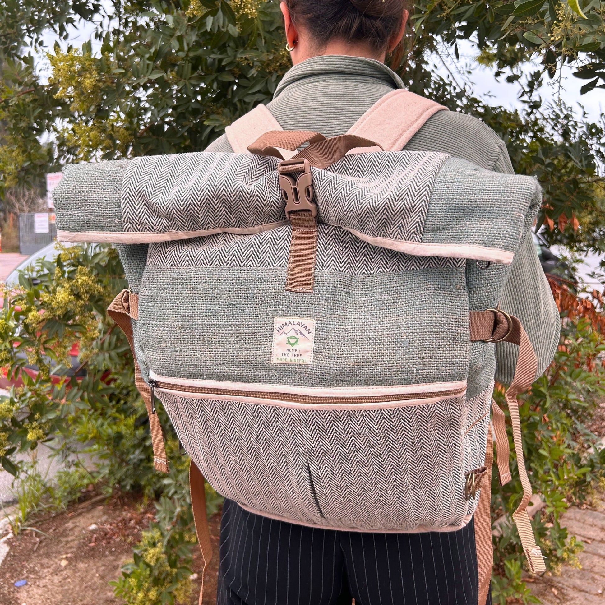 Person wearing a gray backpack with brown straps outdoors