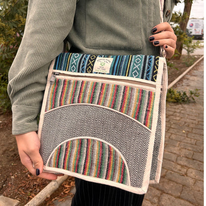 Person holding a colorful striped bag with a brand label outdoors.